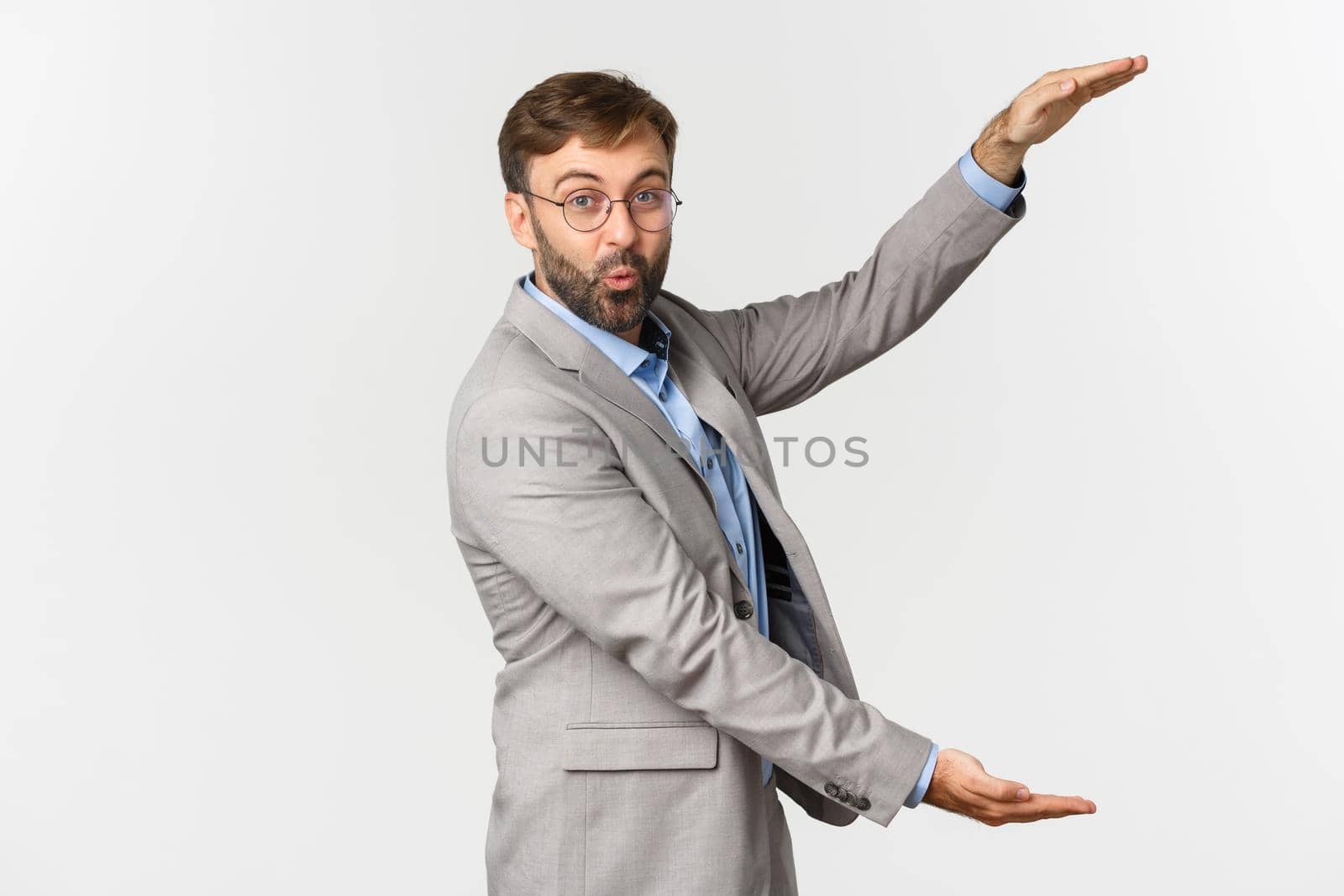 Handsome happy businessman demonstrating chart, showing something large on empty white background, standing over white background.