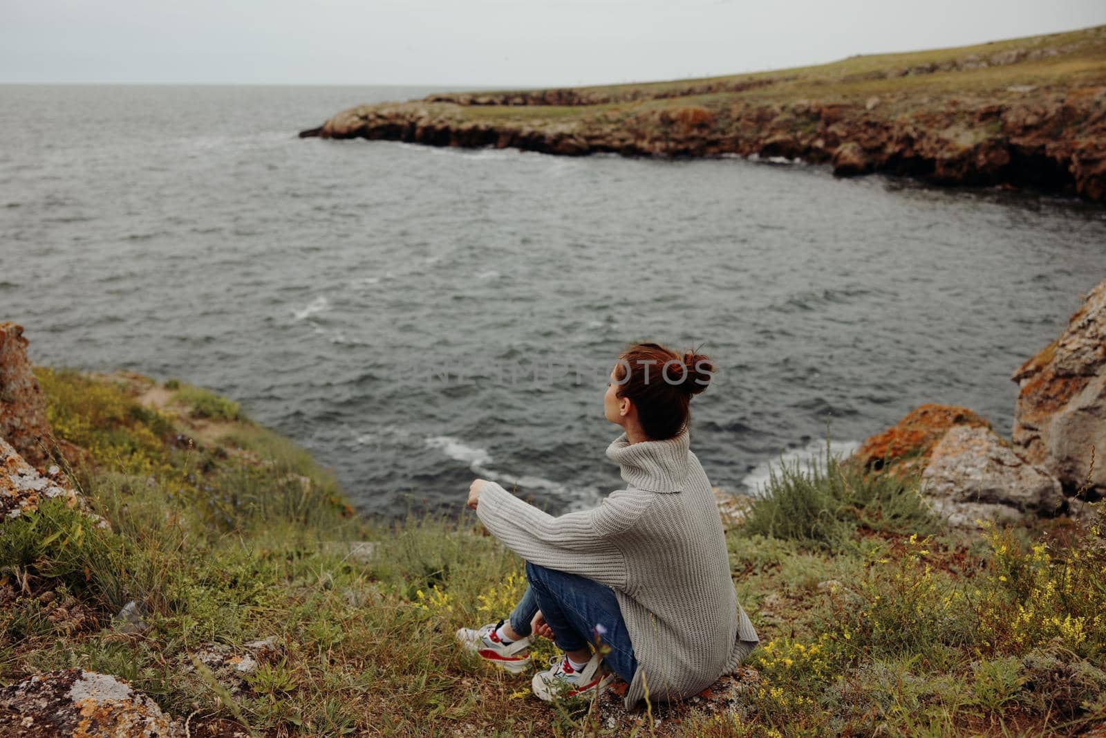 portrait of a woman in a gray sweater stands on a rocky shore nature unaltered. High quality photo