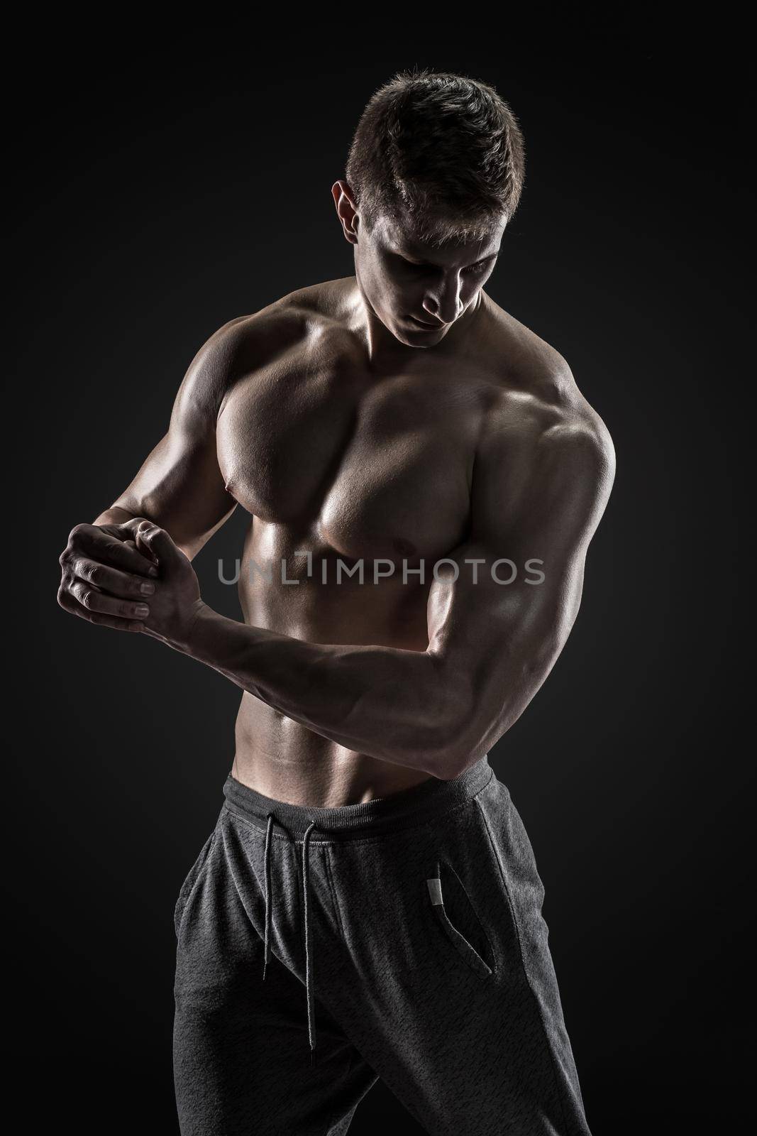 Sporty and healthy man posing and showing his perfect boddy on black background