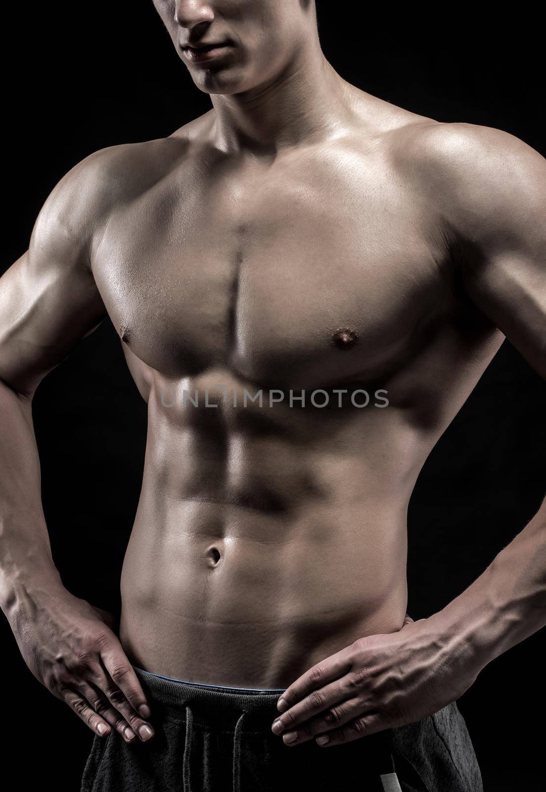 Close-up of a power fitness man. Strong man with muscles and biceps on black background