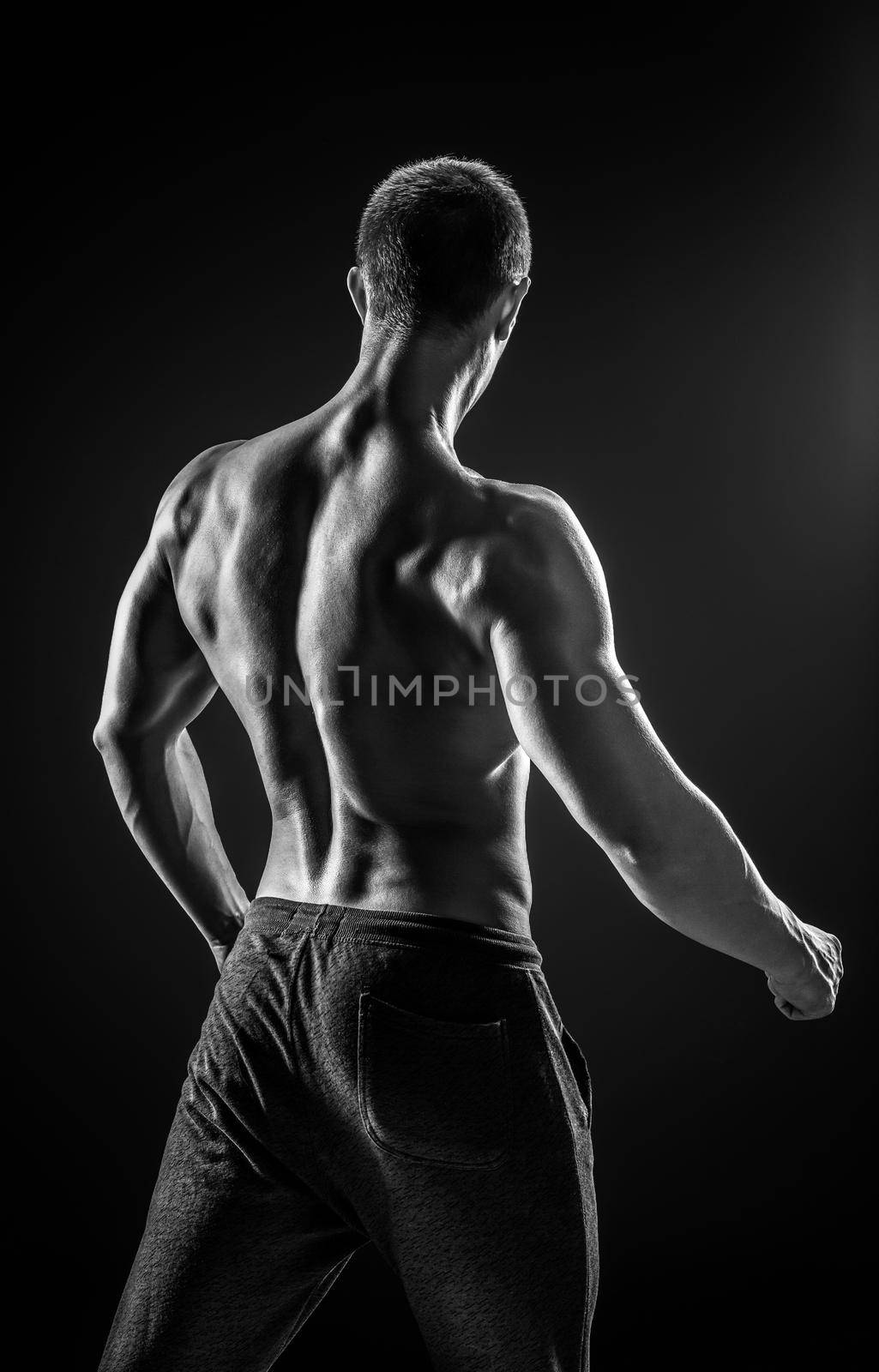 Stunning muscular man fitness model torso showing muscles back and shoulders on black background. Black and white