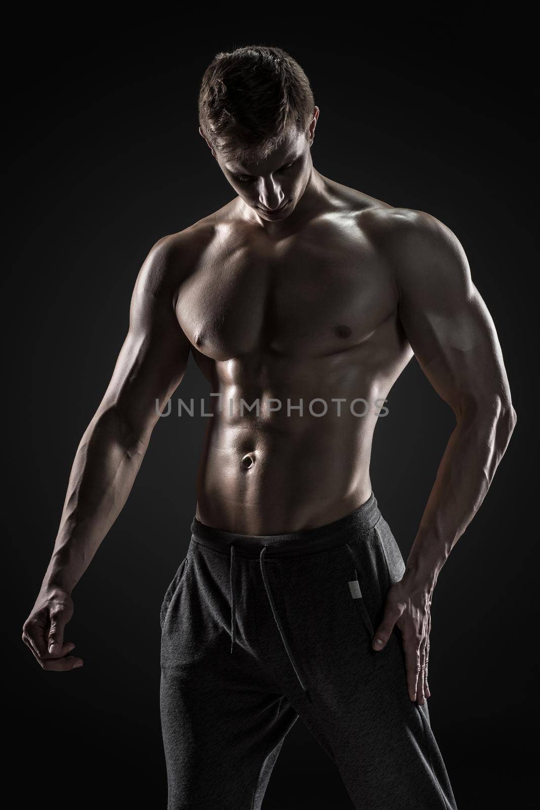 Sporty and healthy man posing and showing his perfect boddy on black background