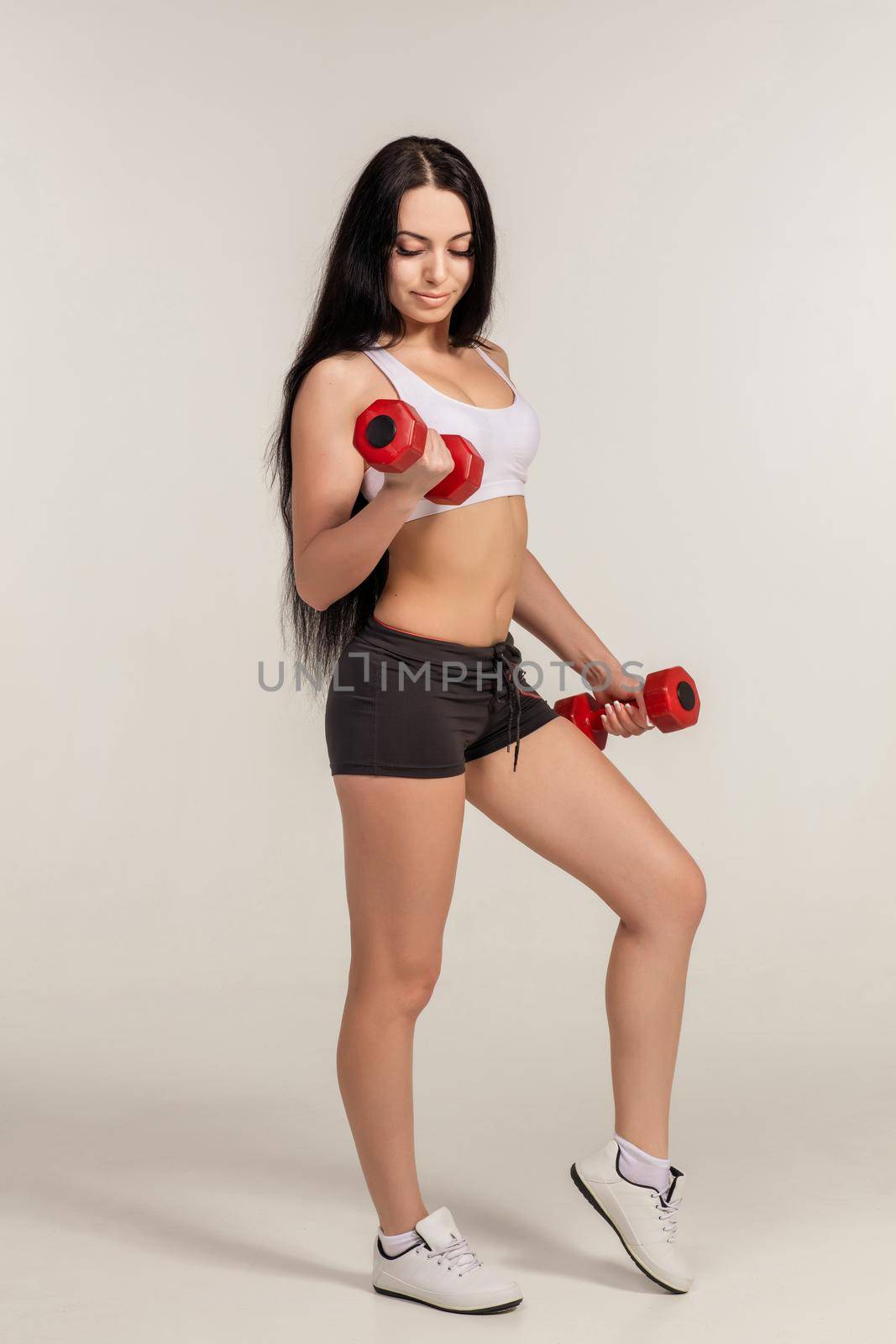 Sports young woman with dumbbells. studio shot