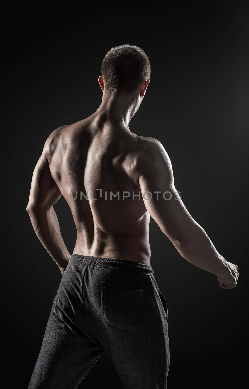 Stunning muscular man fitness model torso showing muscles back and shoulders on black background