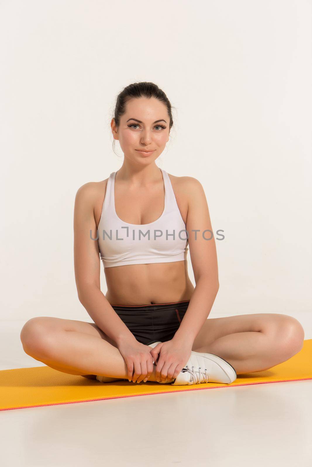 Portrait of young attractive woman doing exercises. Brunette with fit body on yoga mat. Healthy lifestyle and sports concept. Series of exercise poses. look at the camera