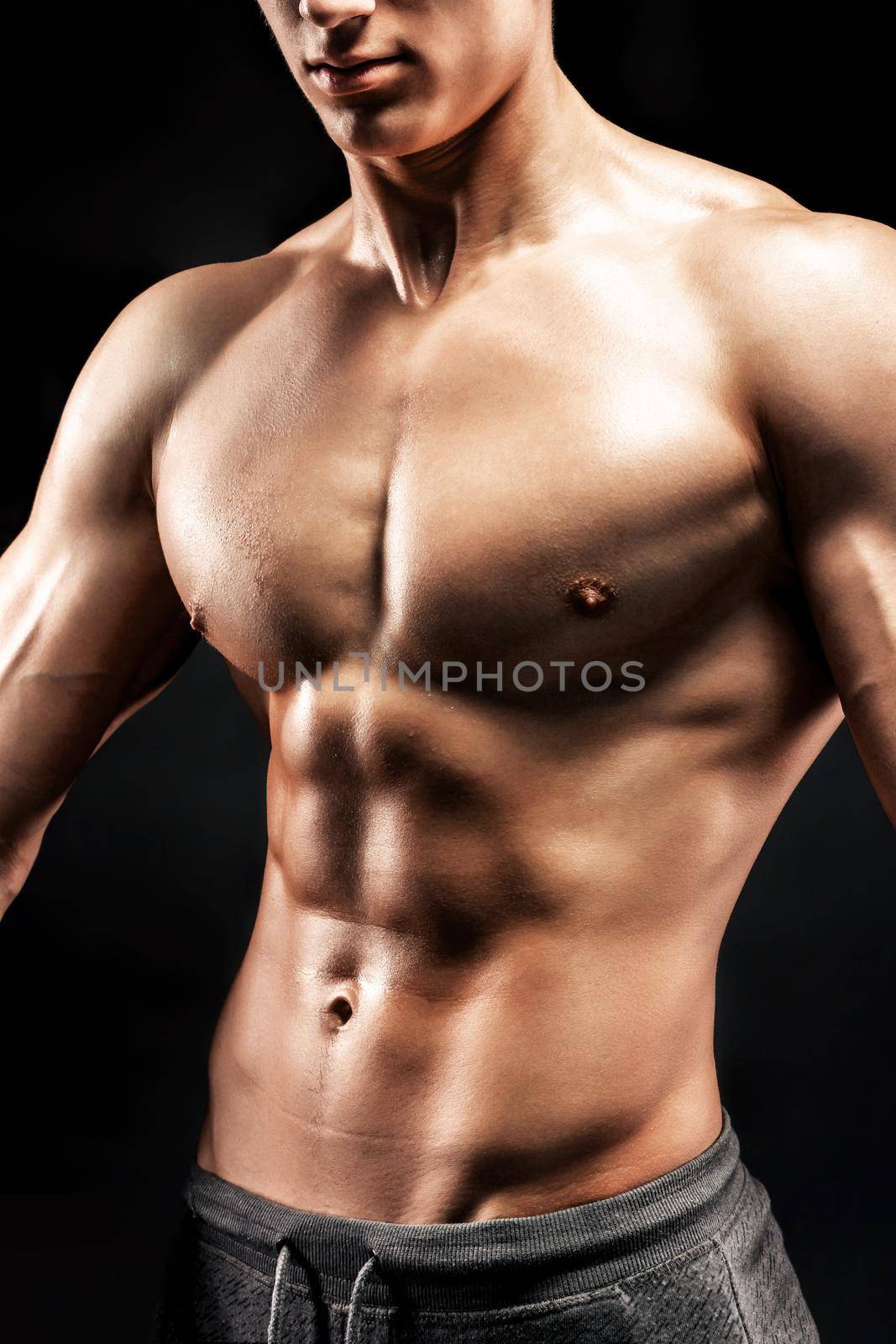 Close-up of a power fitness man. Strong man with muscles and biceps on black background.