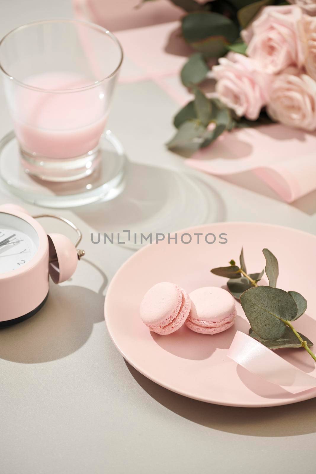 macaroons in pastel colors with bouquet of pink roses flowers on white background. Beautiful holiday background. copy space. by makidotvn