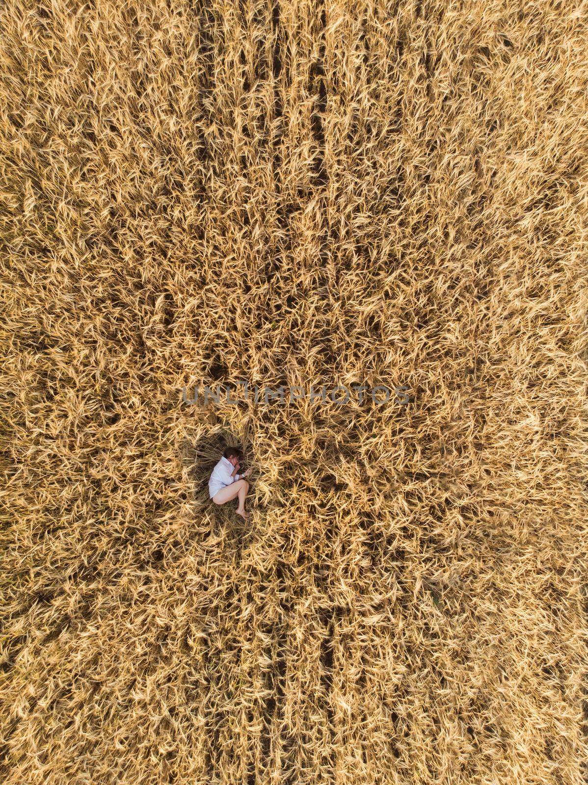 Aerial view of woman lying in the yellow field of wheat