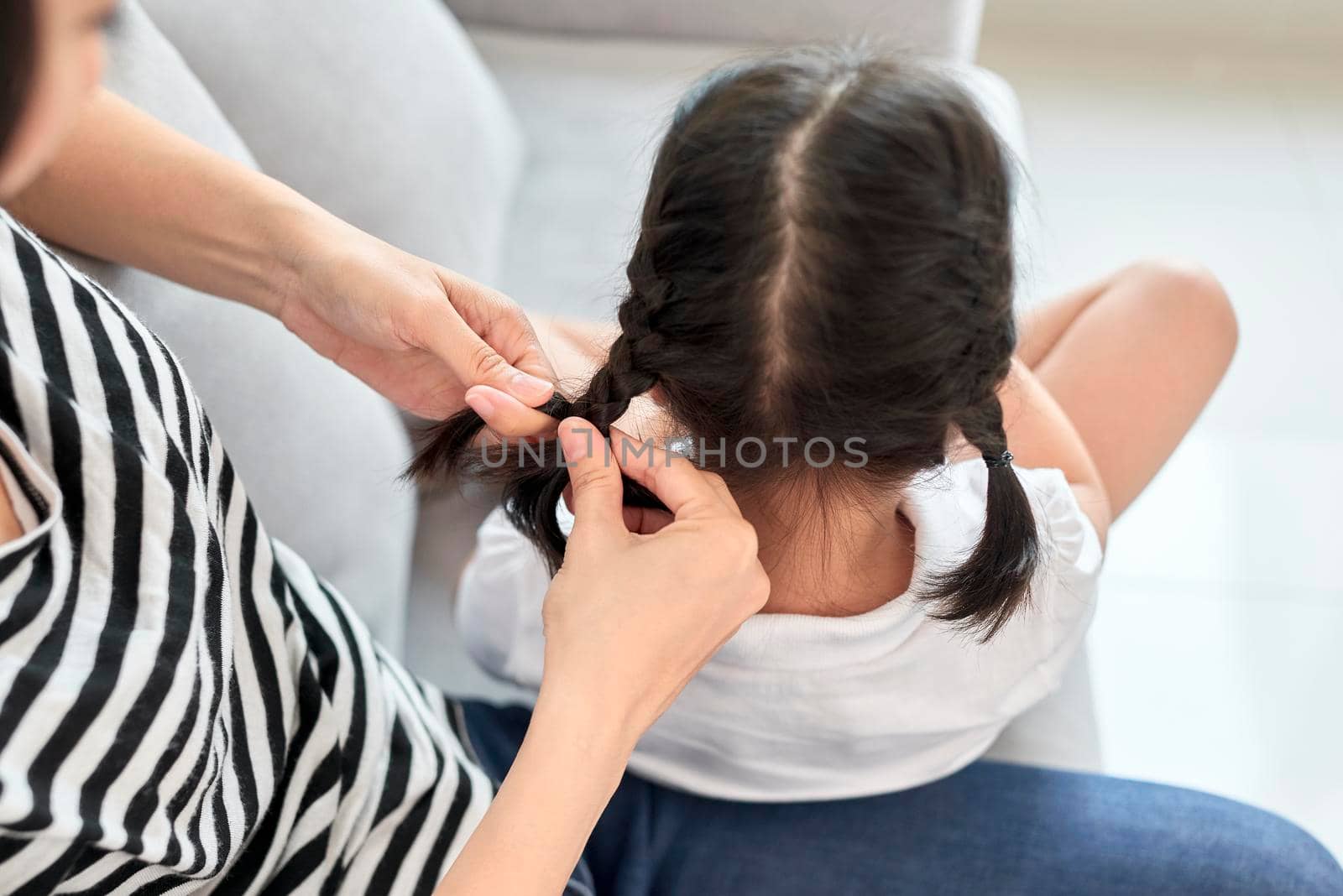 mother braiding hair of her daughter