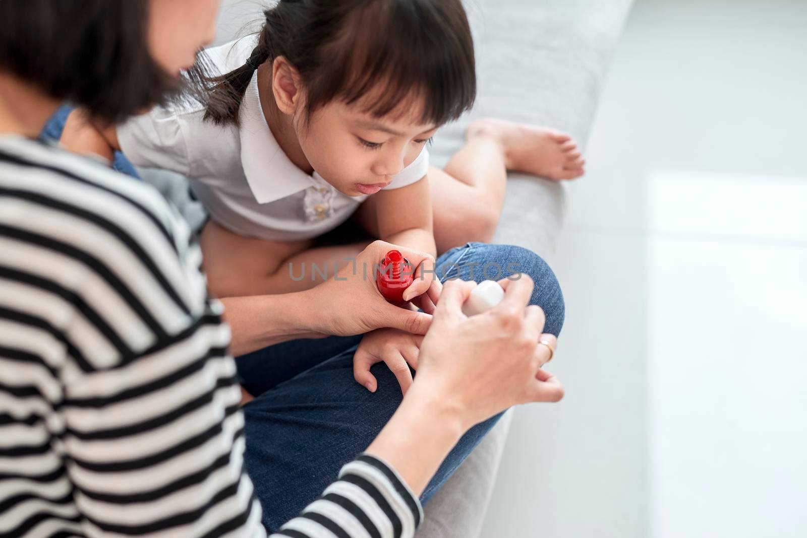 Mother and daughter having fun painting fingernails, family time concept by makidotvn