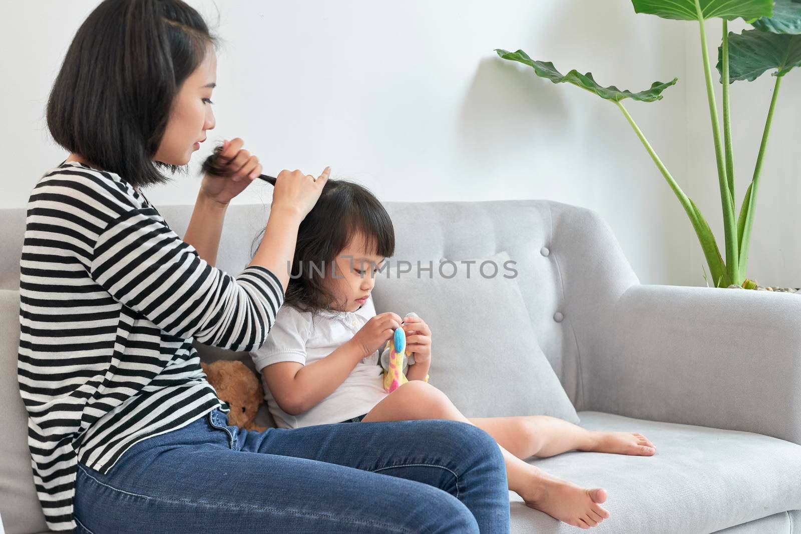mother braiding hair of her daughter