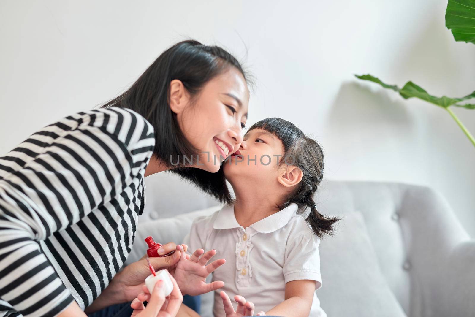 Mother and daughter having fun painting fingernails, family time concept