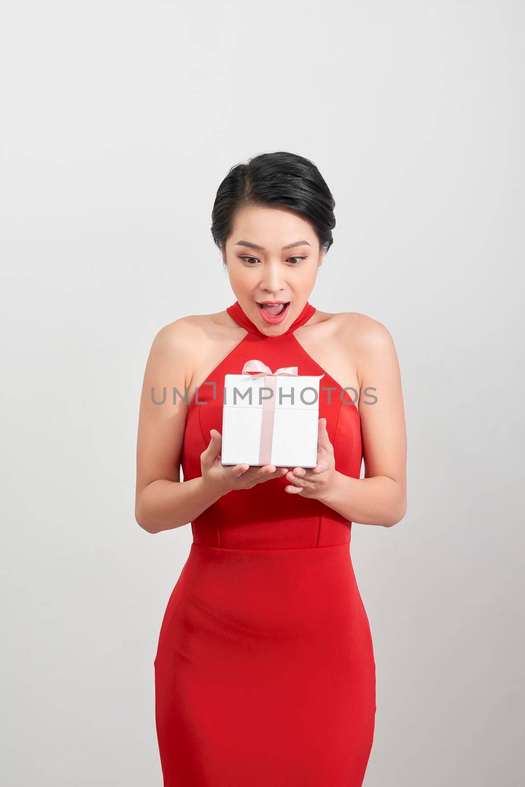 Surprised woman holding gift over white background by makidotvn