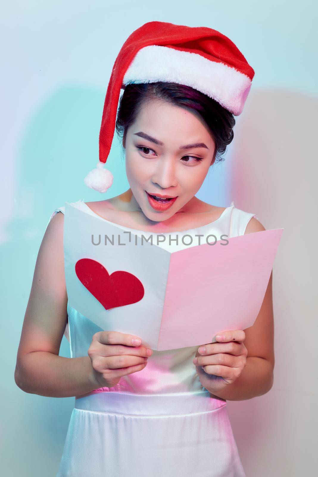 Image of happy beautiful female reading romantic postcard with big red heart by makidotvn