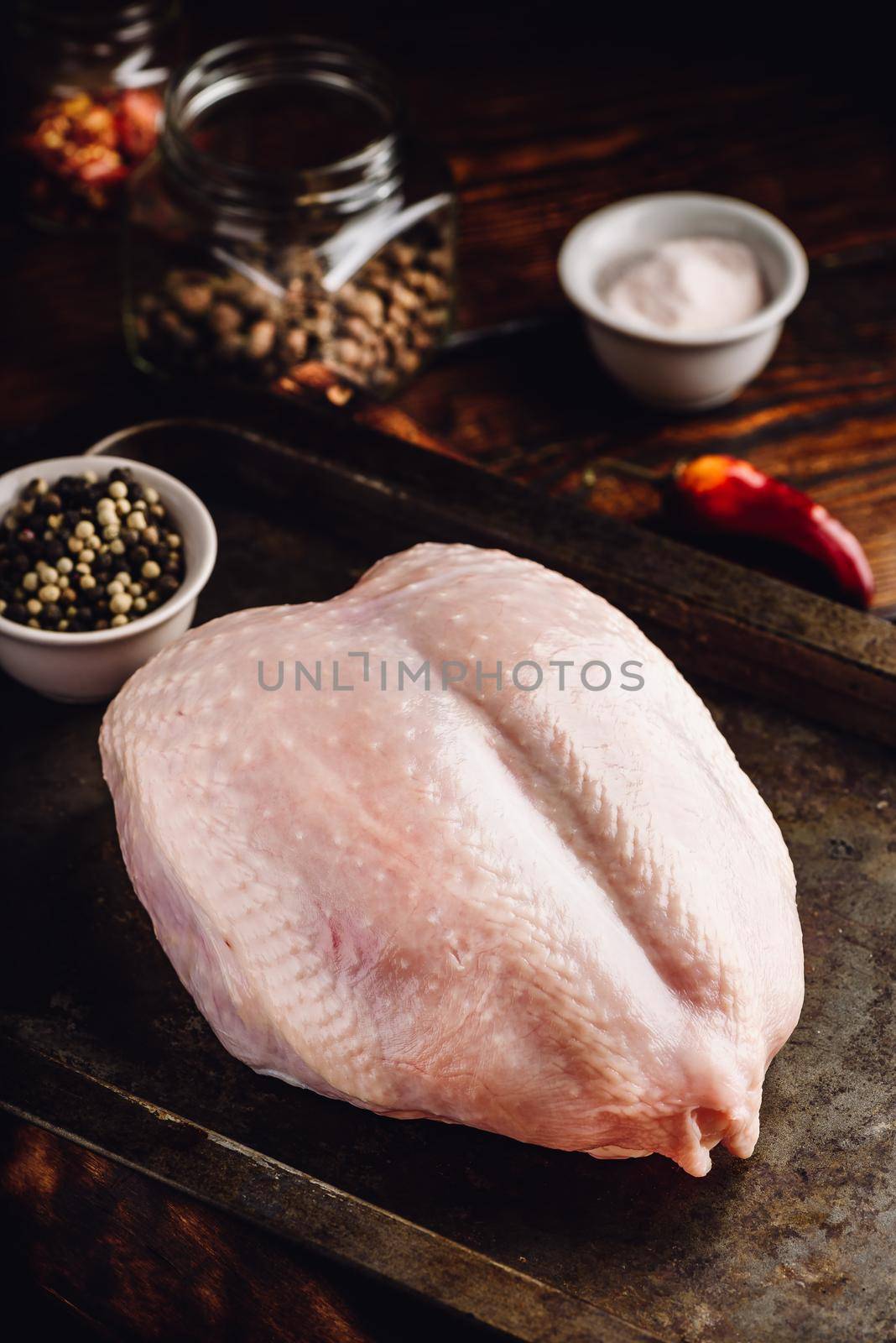 Raw chicken breast with spices on baking tray