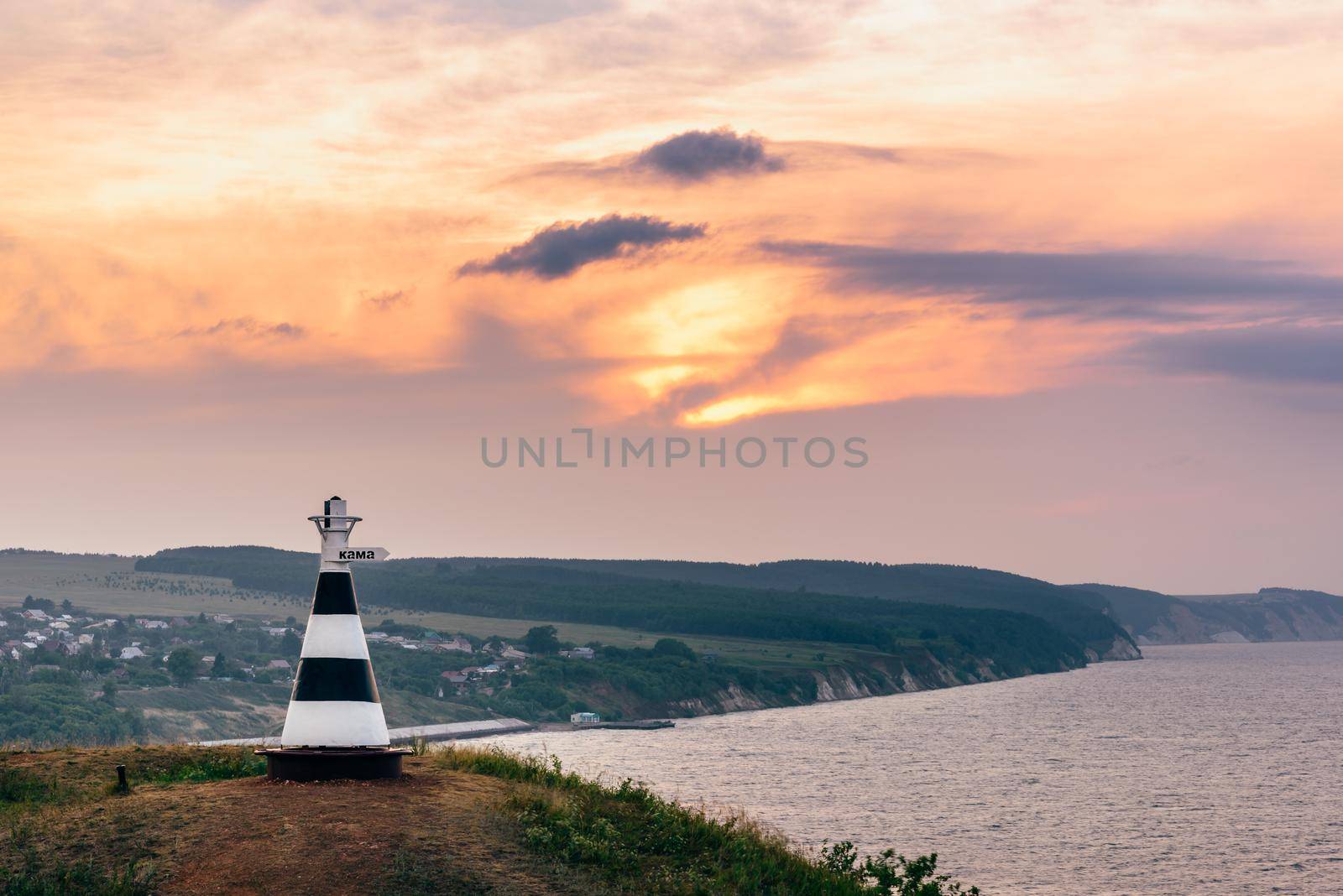 Beacon with the inscription 'Kama' on the hill in sunset light