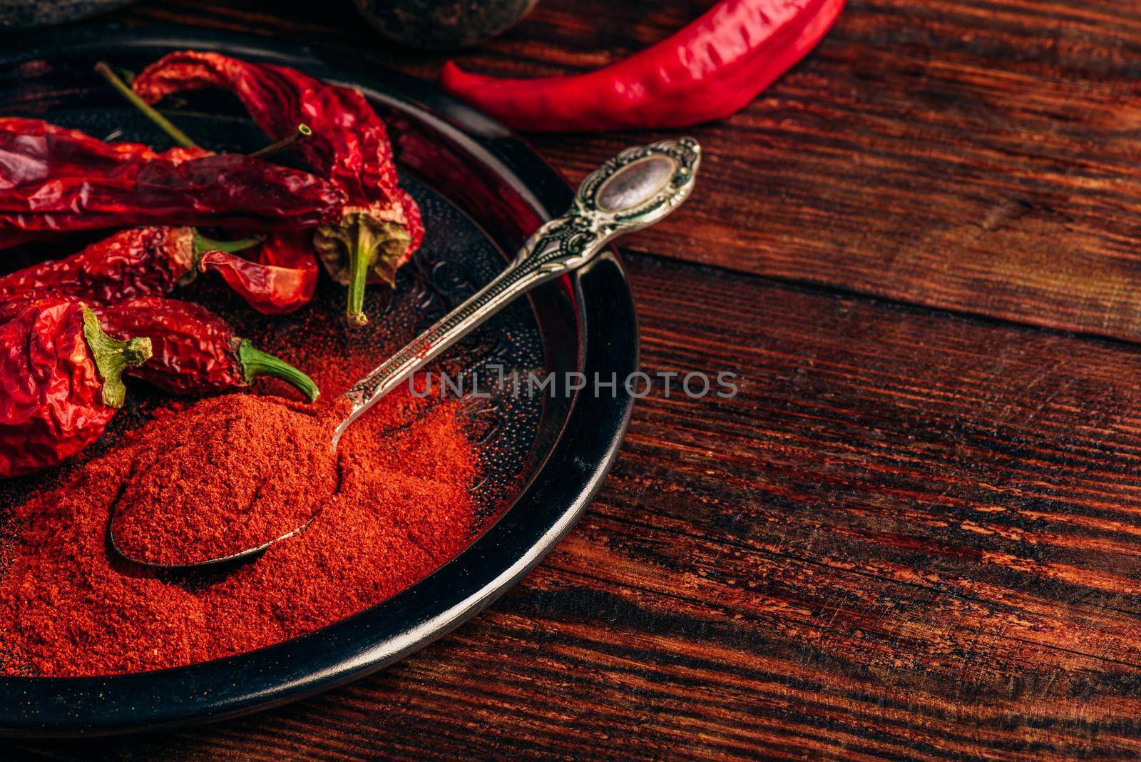 Spoonful of chili pepper powder with dried fruits on metal plate. Copy space