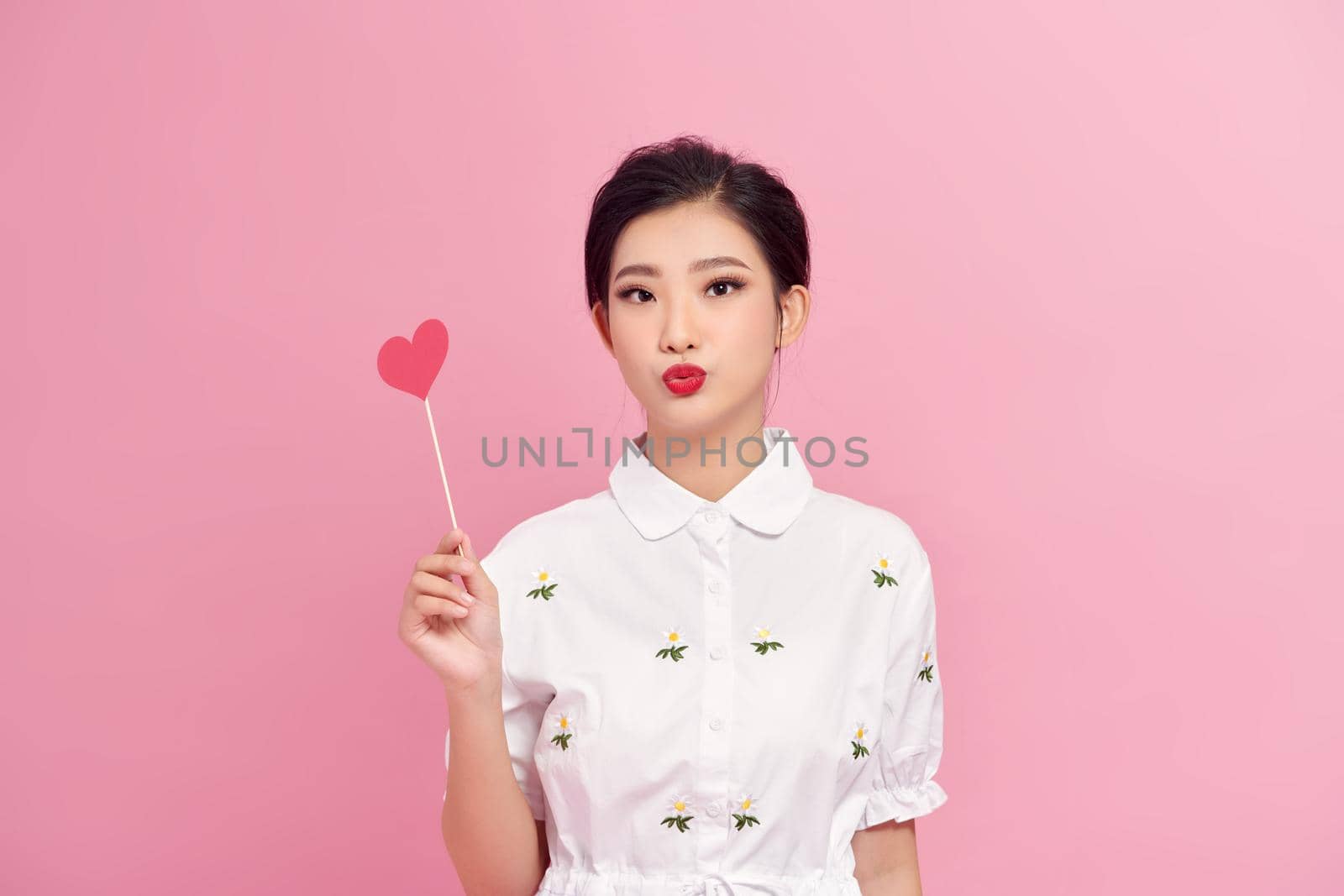 Portrait of pretty girl holding red paper heart on stick