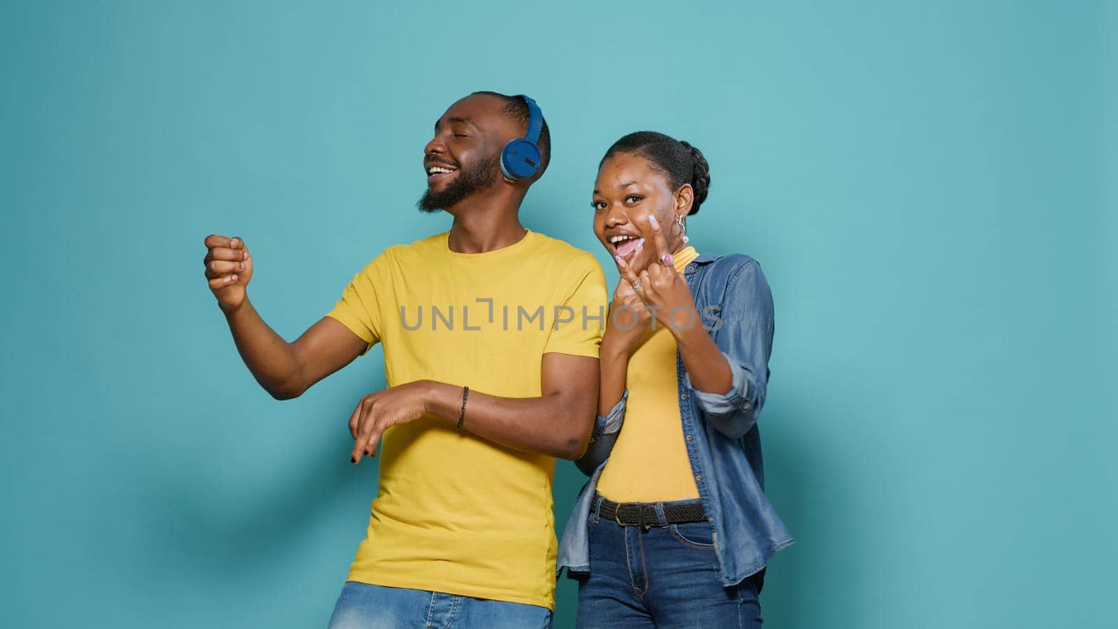 Man with headphones playing air guitar and woman showing rock sign by DCStudio