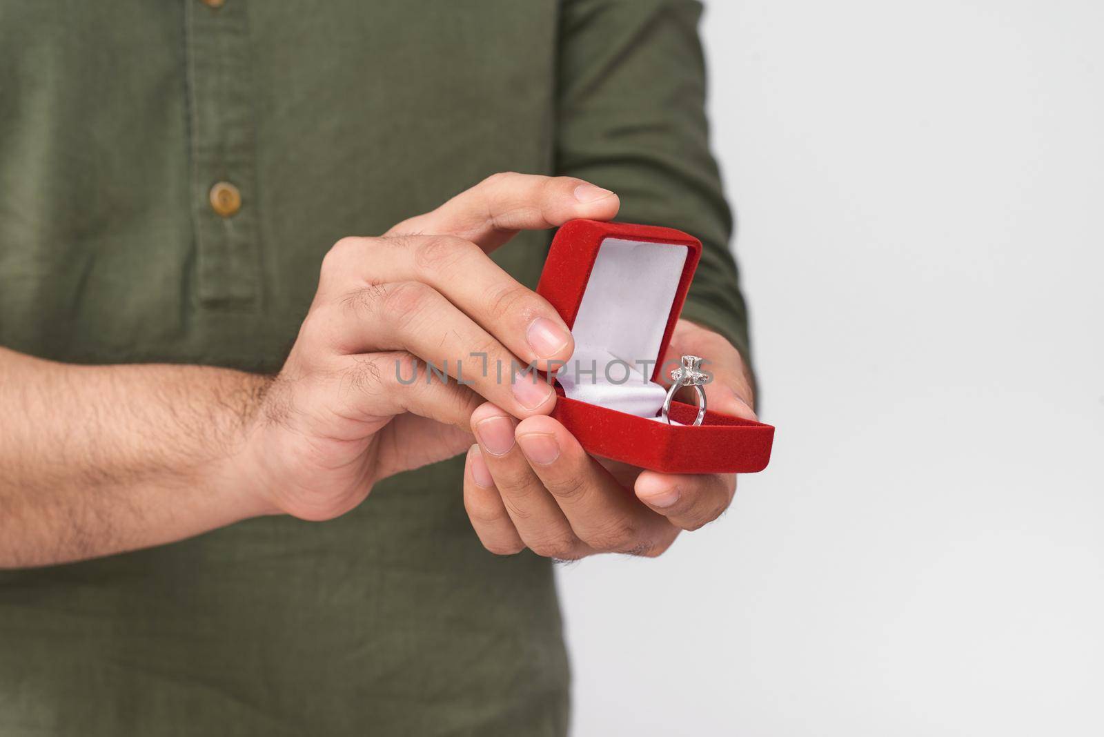 Close up of male hands holding wedding ring and gift box.