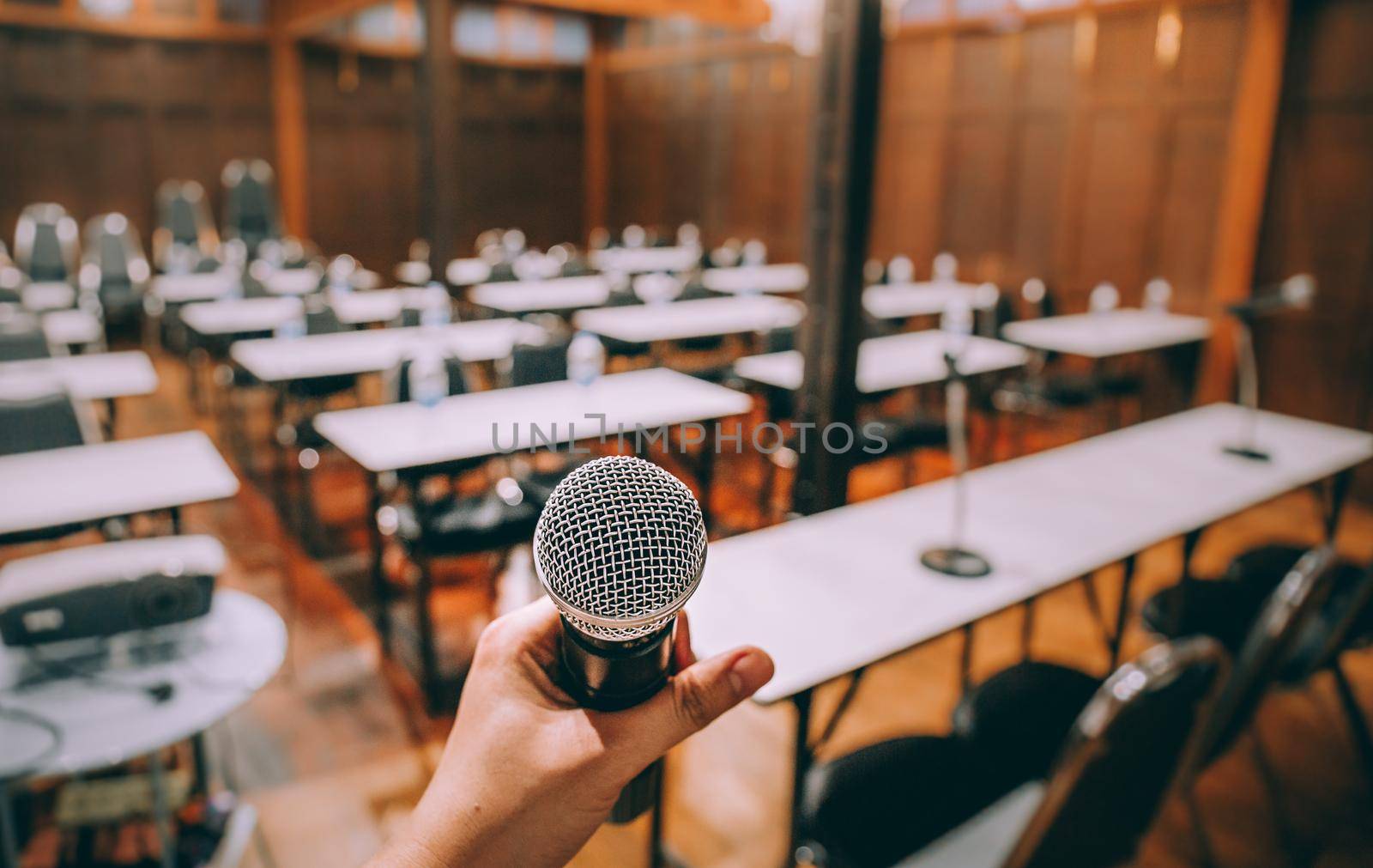 Close-up microphone with blurred people attending seminar background