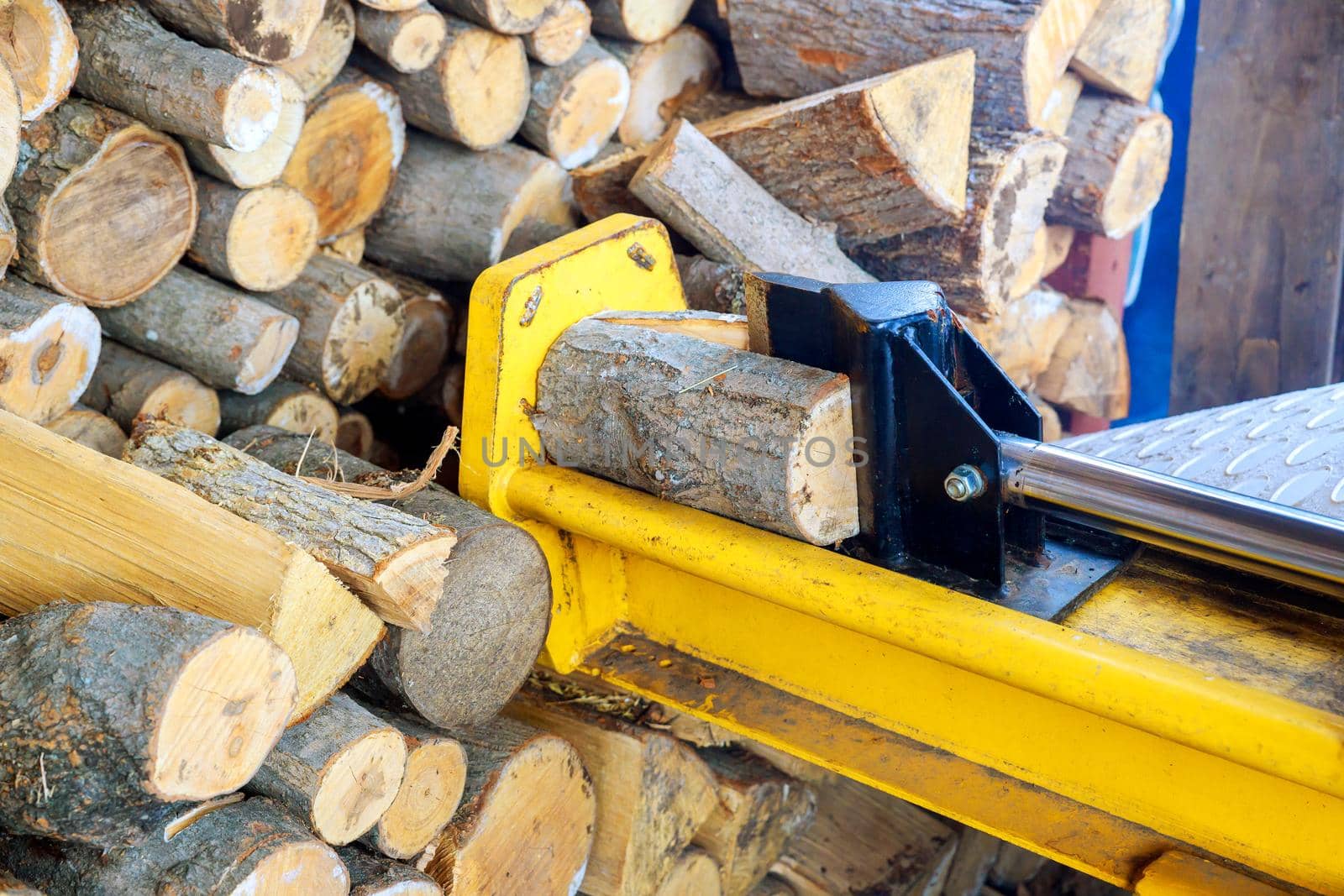 A man working with the firewood to split the logs by the machine by ungvar