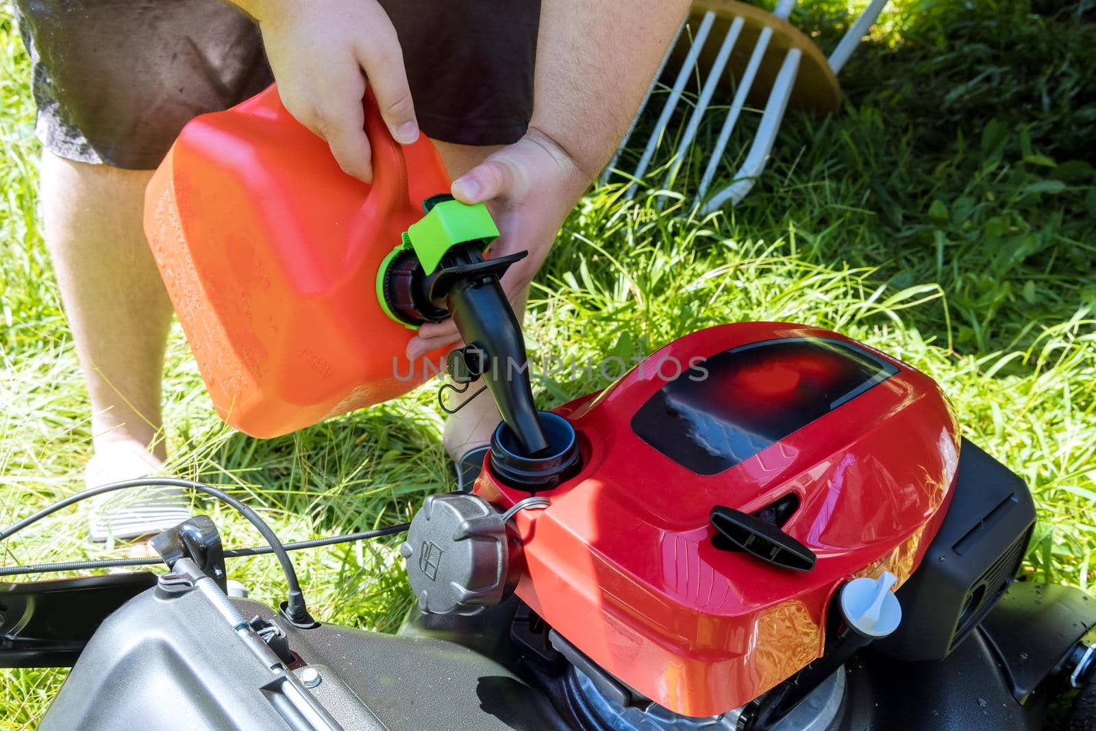 Pouring gasoline gallon refueling into the tank of lawn mower