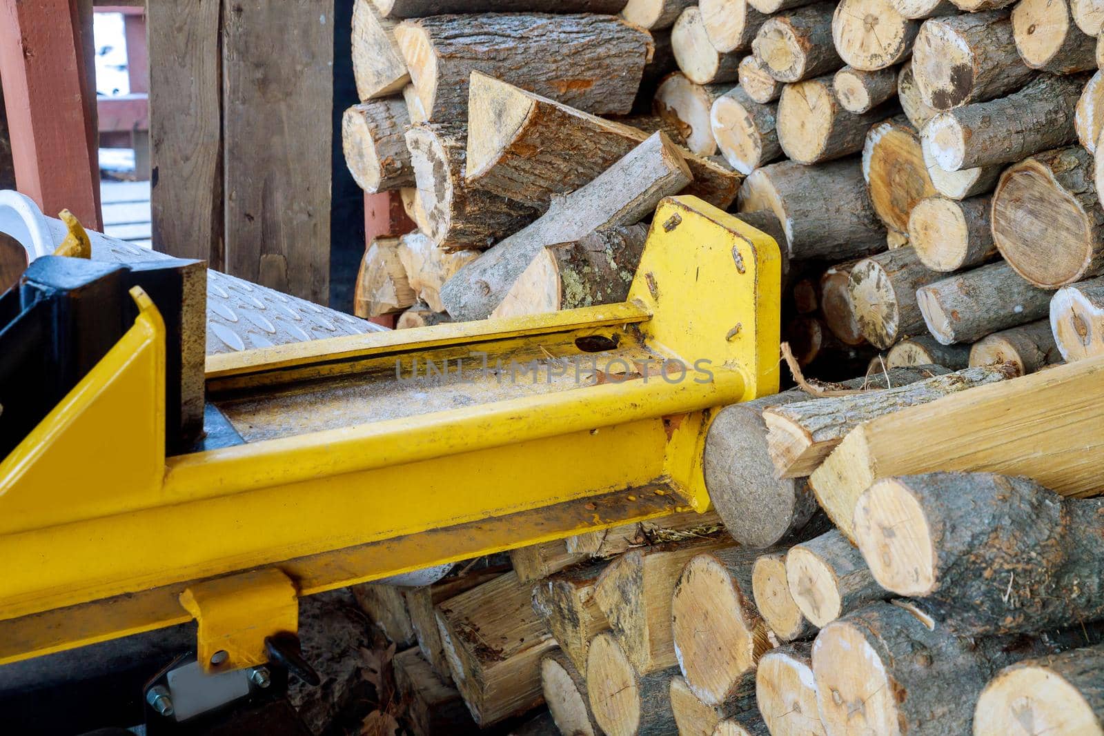 Splitter machine with person splitting firewood to split the logs
