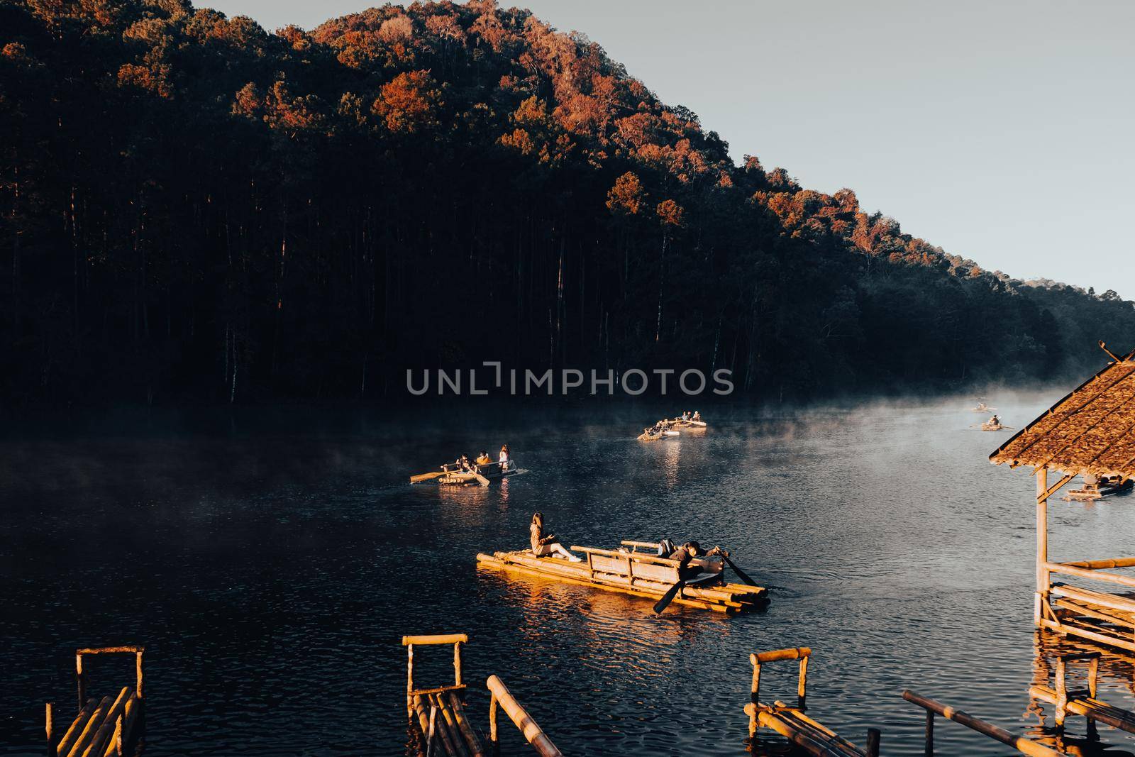 Mae Hong Sorn, Thailand - December 17, 2021 : Beautiful lake over the misty river at sunrise with traveler on the Bamboo raft. Morning view at Pang Oung Lake (Pang Tong reservoir), Mae hong son, Thail by TEERASAK