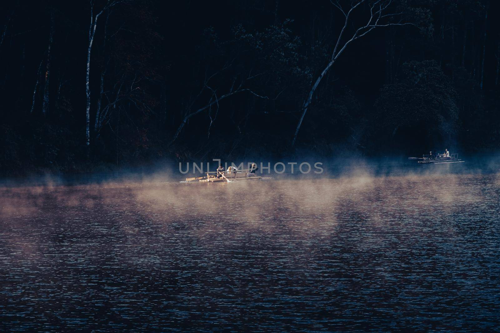 Mae Hong Sorn, Thailand - December 17, 2021 : Beautiful lake over the misty river at sunrise with traveler on the Bamboo raft. Morning view at Pang Oung Lake (Pang Tong reservoir), Mae hong son, Thail by TEERASAK