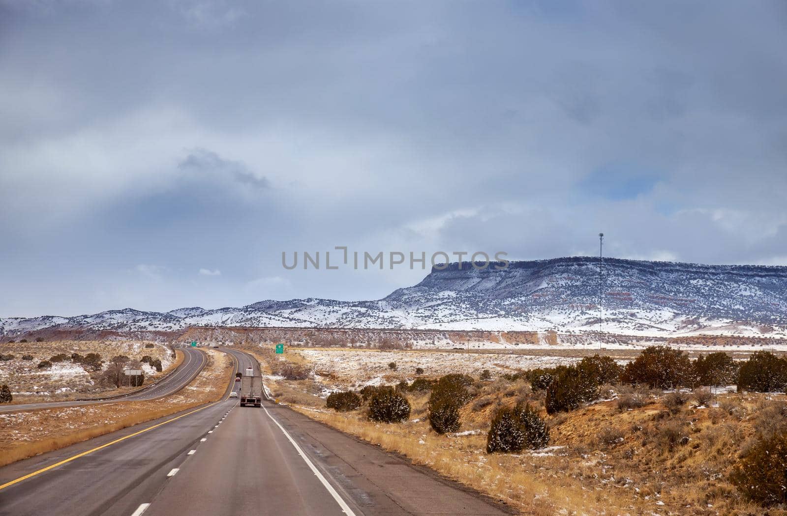 Snow covered red rock mountain with overcast sky in I-40 highway New Mexico