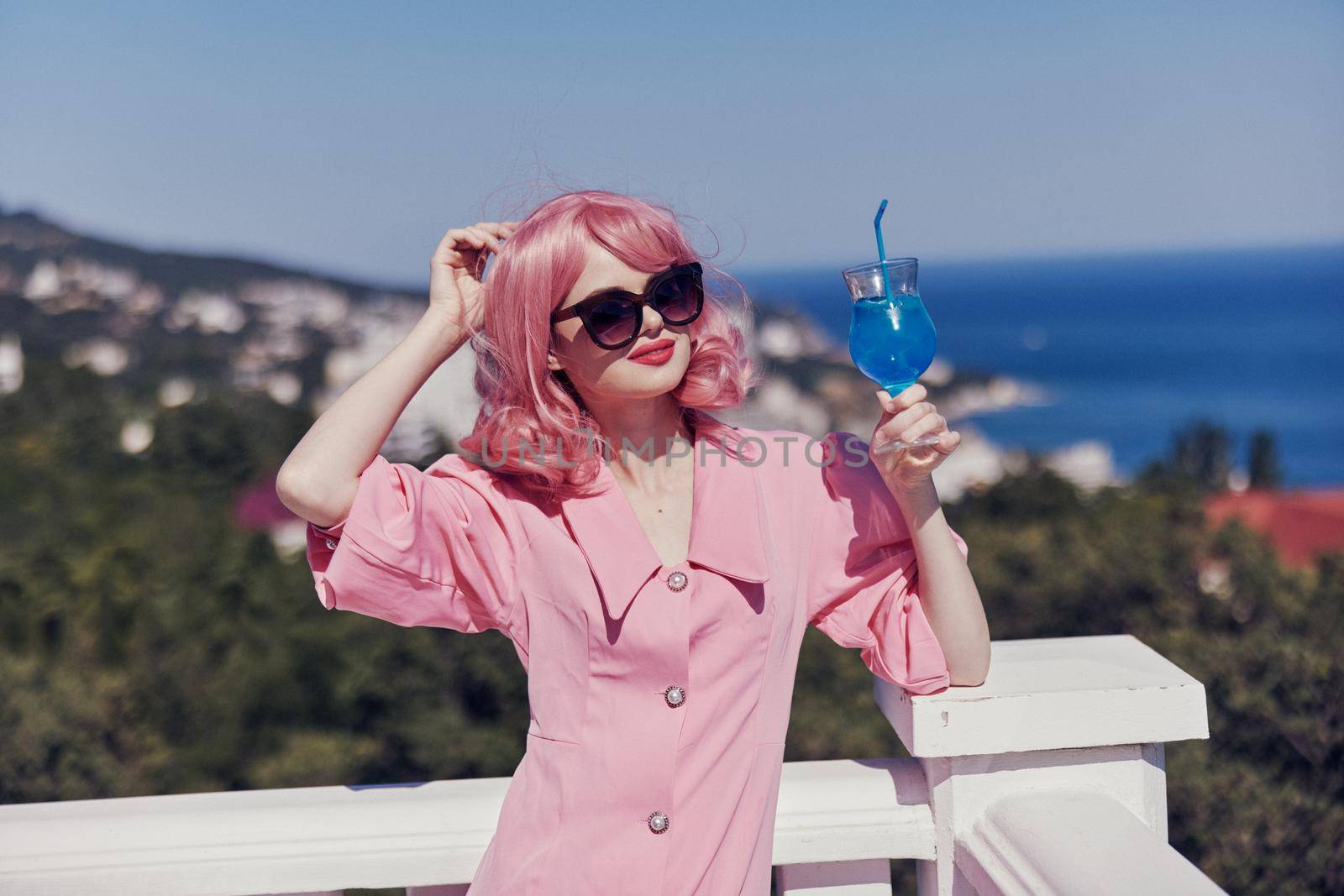 fashionable woman enjoying a colorful cocktail on the panoramic view hotel terrace sunny day. High quality photo