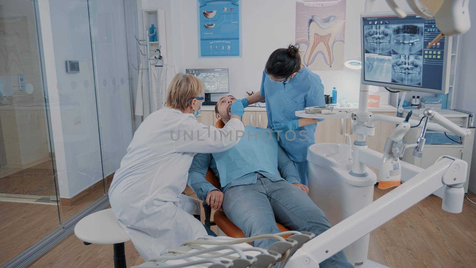 Dentist and assistant doing consultation with dental tools by DCStudio