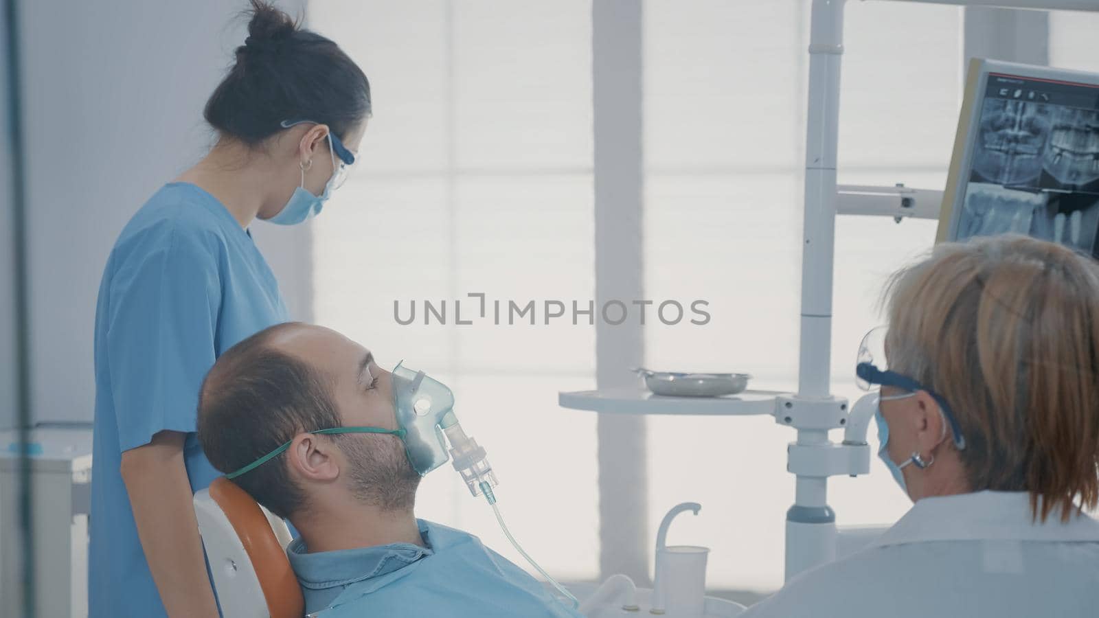 Oral care worker giving oxygen mask with anesthesic to patient by DCStudio