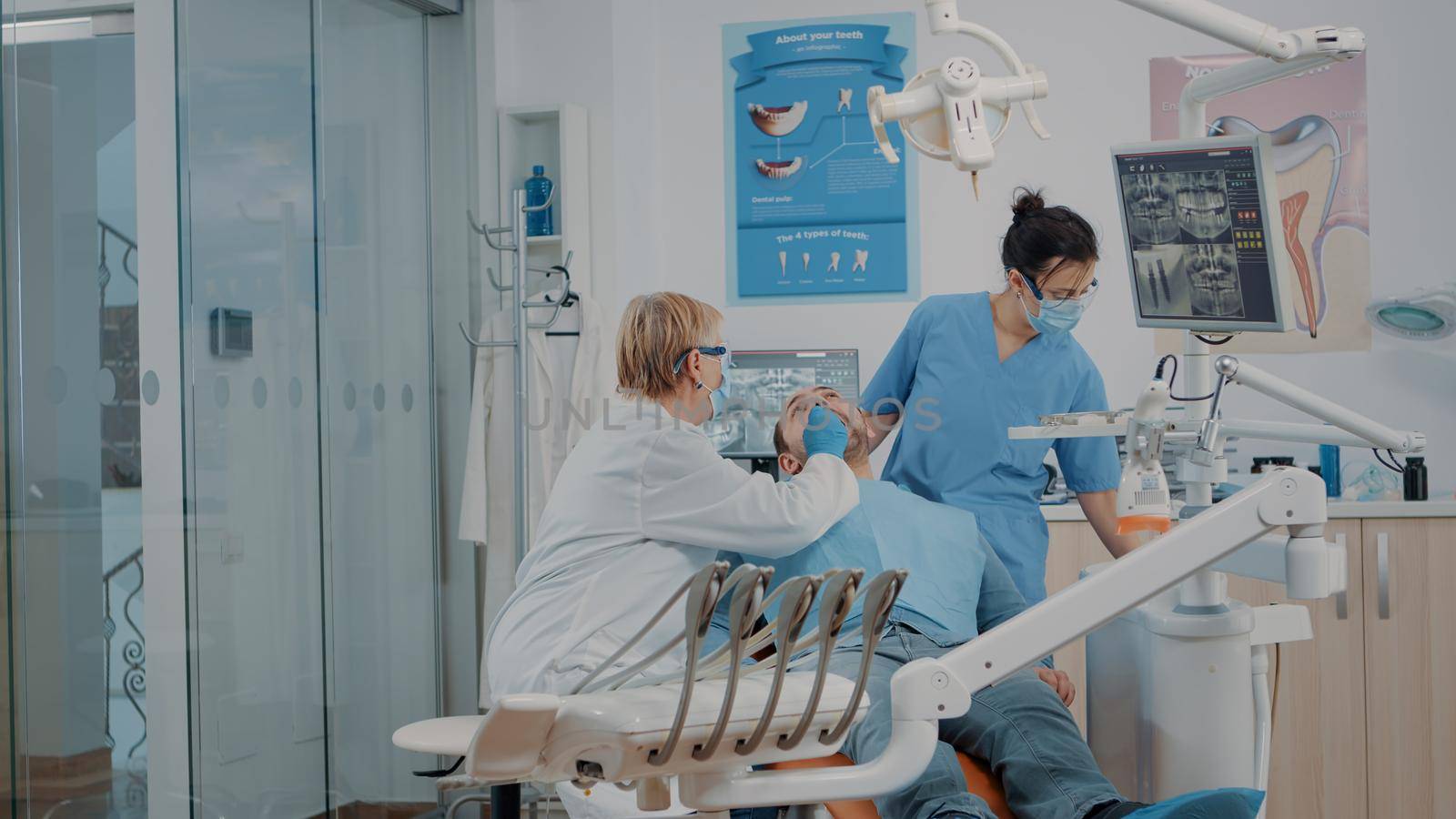 Dentist and nurse examining teeth of patient in dentistry cabinet, doing consultation to find caries and cavity problems. Team of experts using dental tools and instruments at checkup.