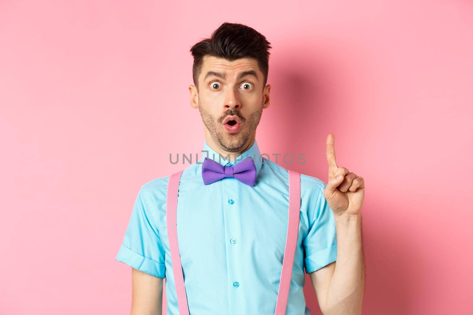Creative man pitching an idea, saying suggestion with raised finger, standing on pink background.
