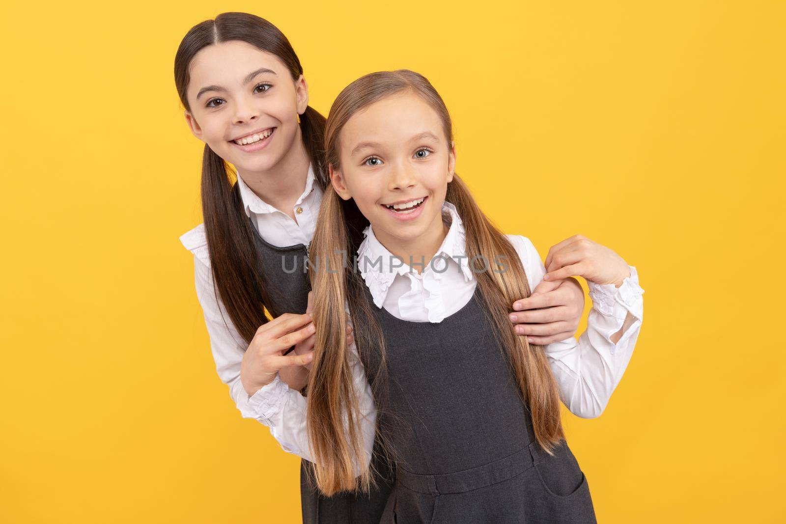 Happy school kids with beauty look wear long hair in formal uniforms yellow background, salon.