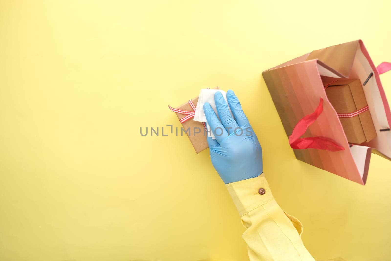 hand in latex gloves wapping a gift box with tissue .