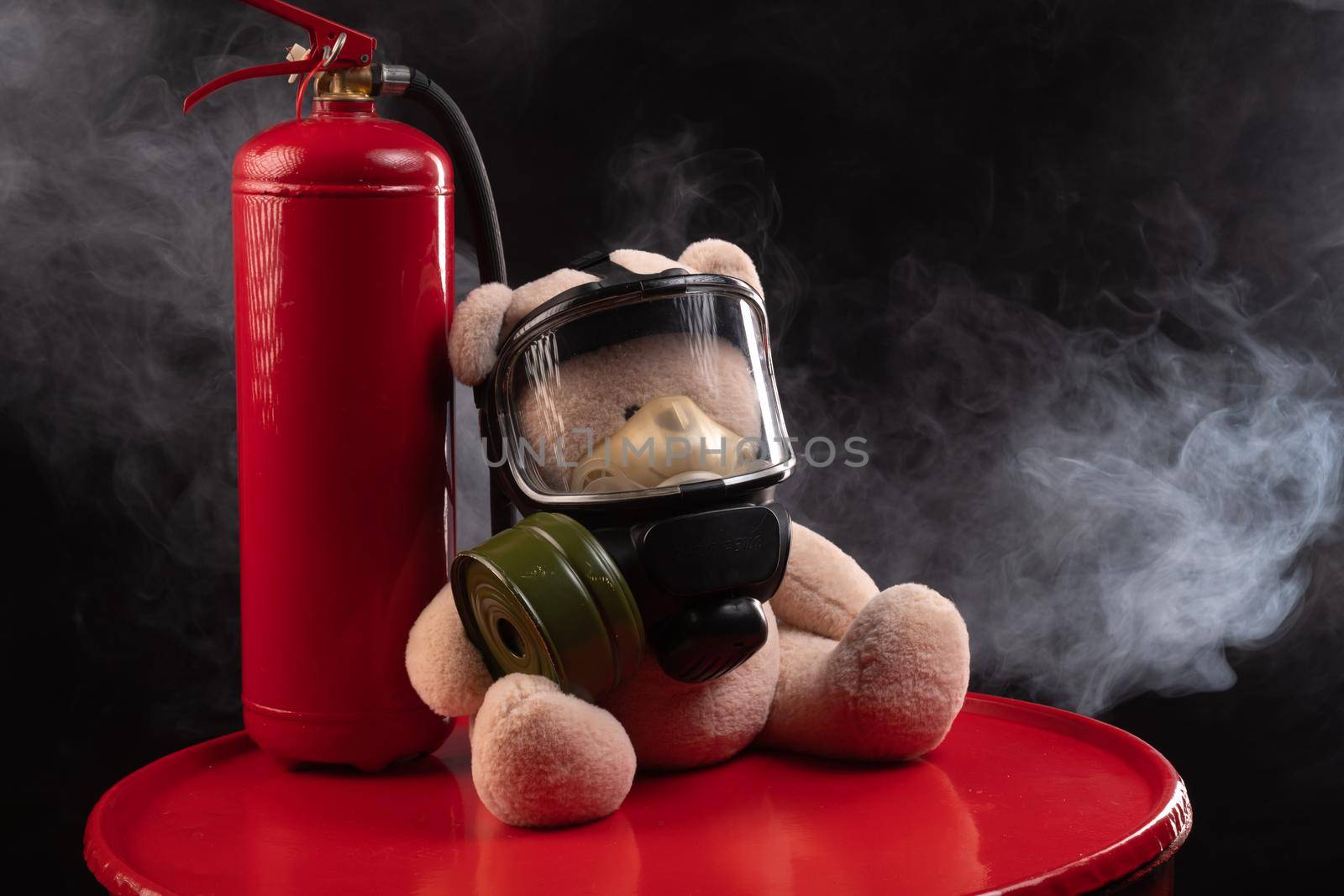 mascot of the fire brigade is a teddy bear in a gas mask with a fire extinguisher in smoke on a dark background