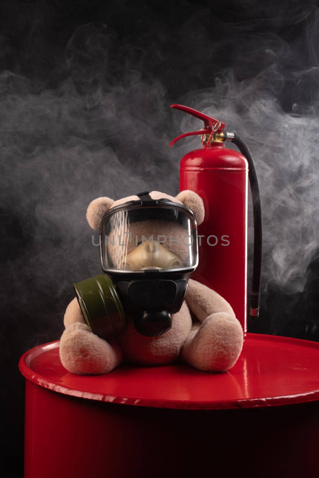 mascot of the fire brigade is a teddy bear in a gas mask with a fire extinguisher in smoke on a dark background