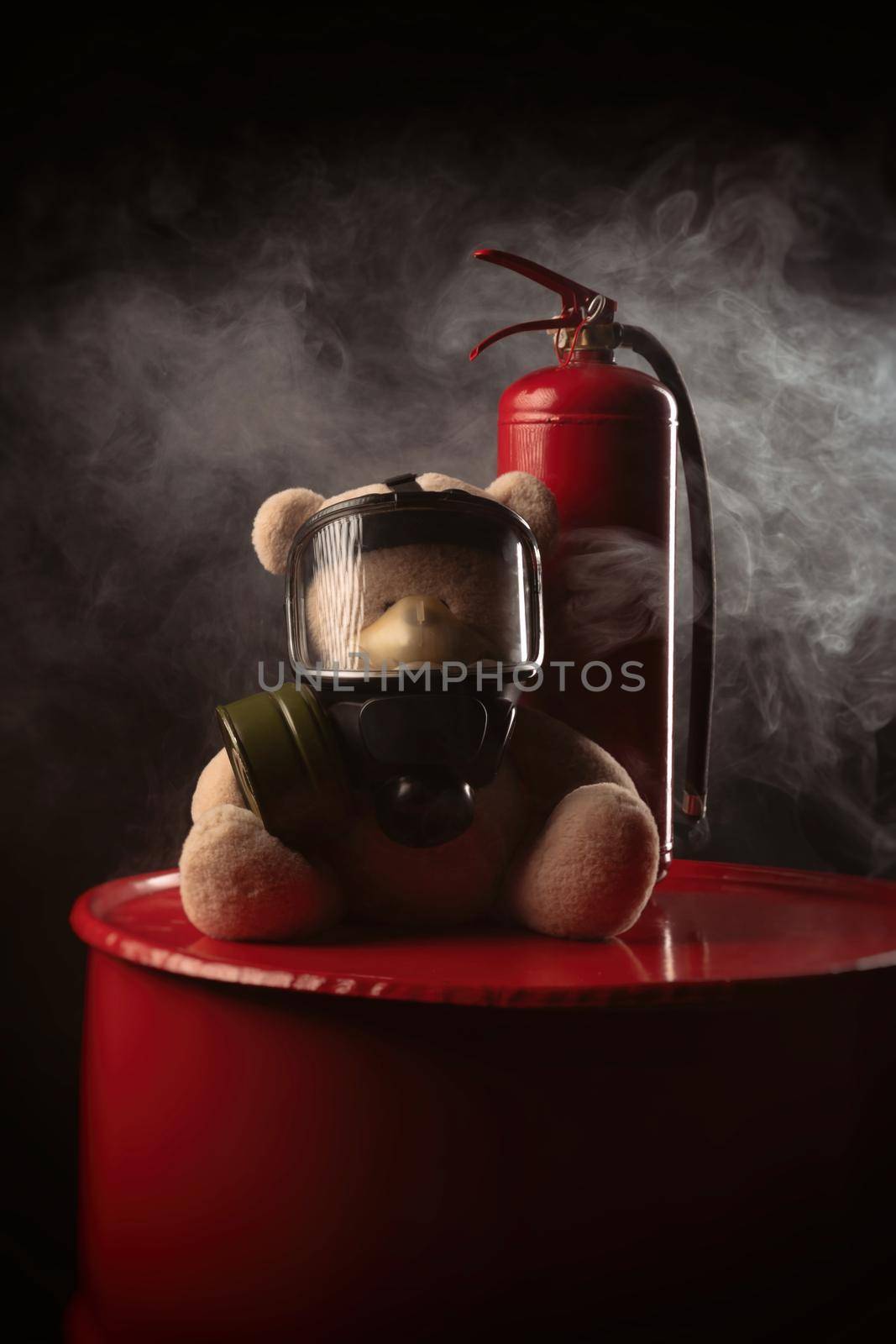 mascot of the fire brigade is a teddy bear in a gas mask with a fire extinguisher in smoke on a dark background