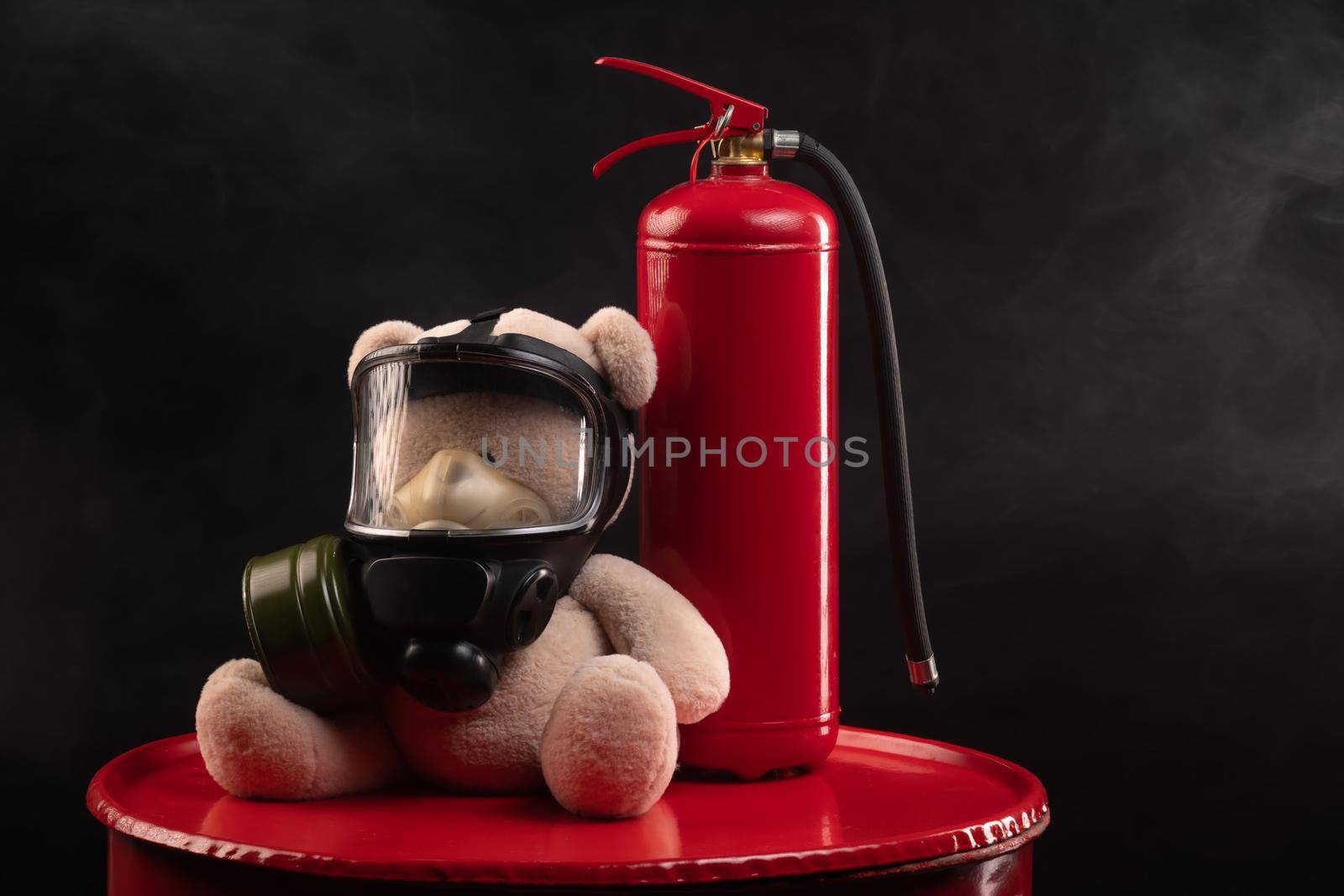 mascot of the fire brigade is a teddy bear in a gas mask with a fire extinguisher in smoke on a dark background