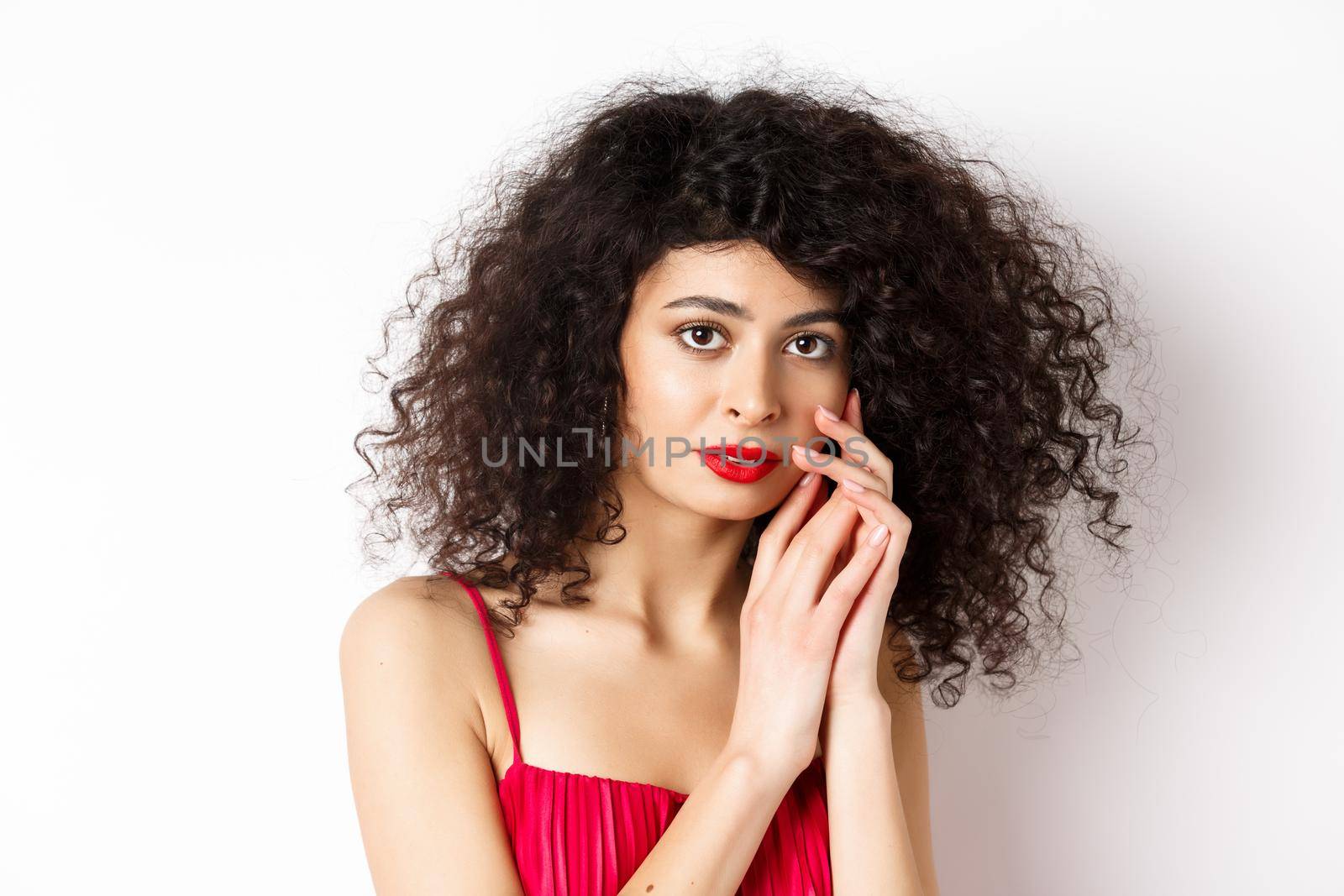 Close-up of tender romantic woman, gently touching face and looking sensual at camera, white background.