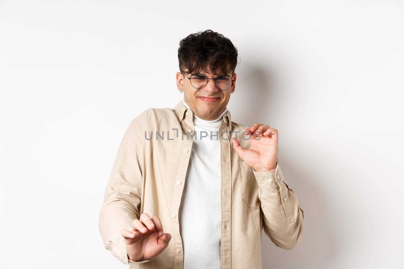 Disgusted guy grimacing and jumping away from something nasty, stare with aversion and dislike, rejecting bad offer, standing on white background.