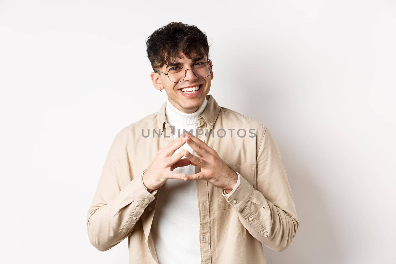 Portrait of hipster guy in glasses with white smile, steeple fingers as having plan, scheming something interesting, standing cunning on white background.