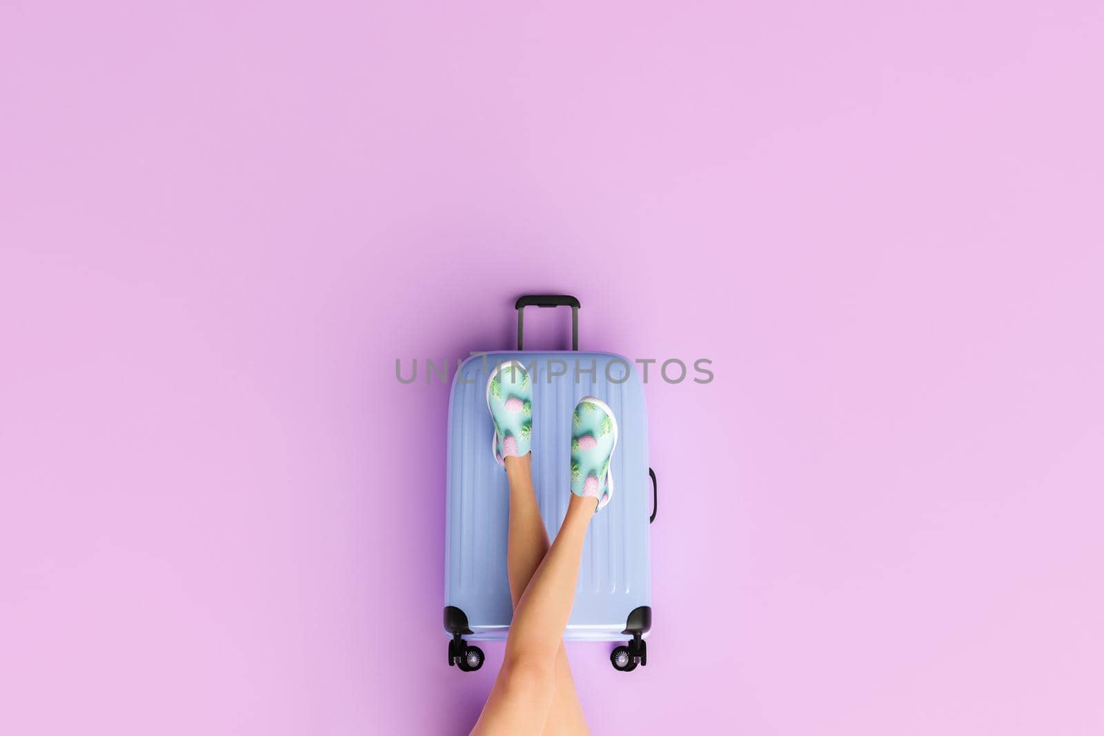 travel suitcase with female legs on top in a minimal scene by asolano