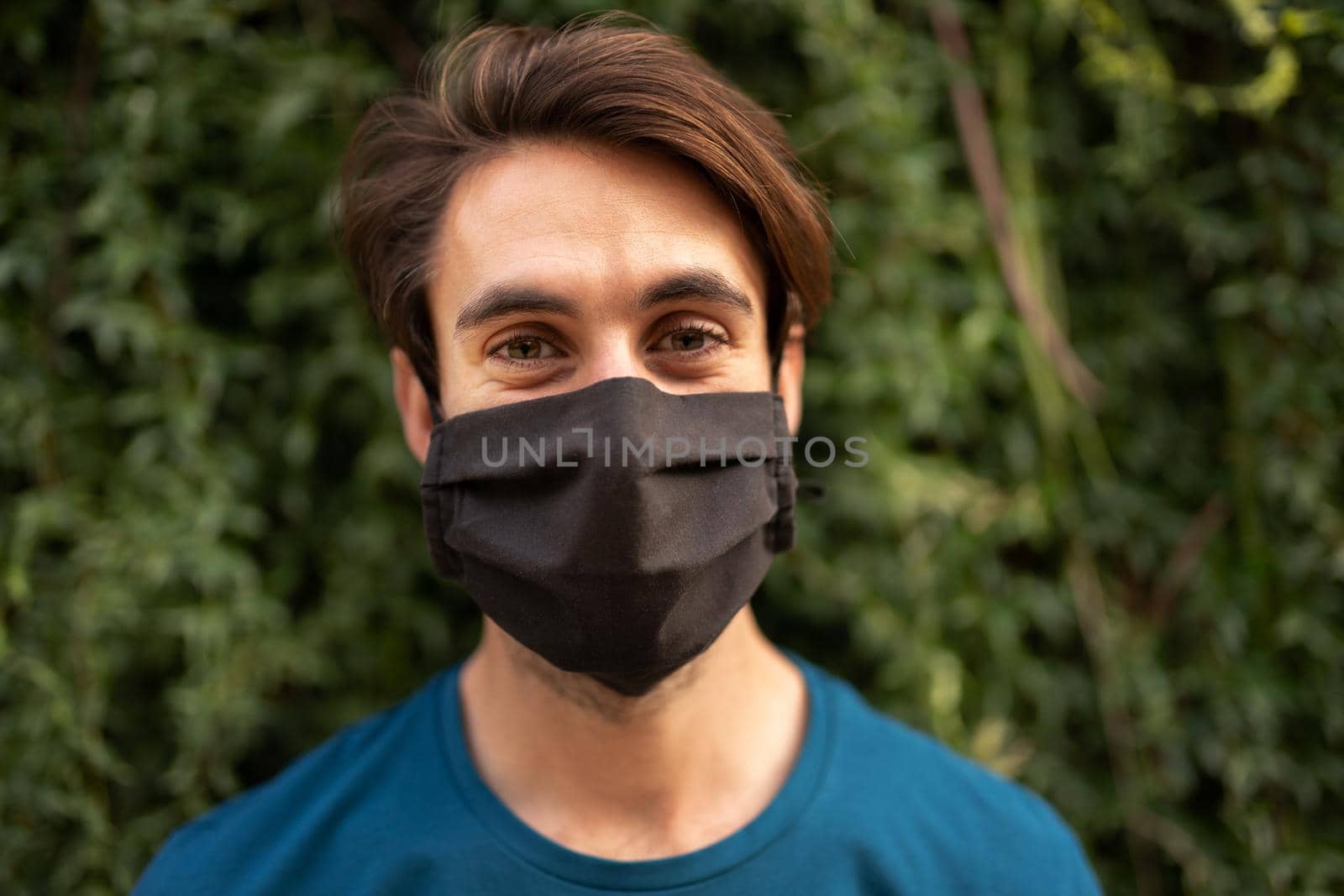 Portrait of young caucasian man wearing protective face mask looking at camera. Copy space. by Hoverstock