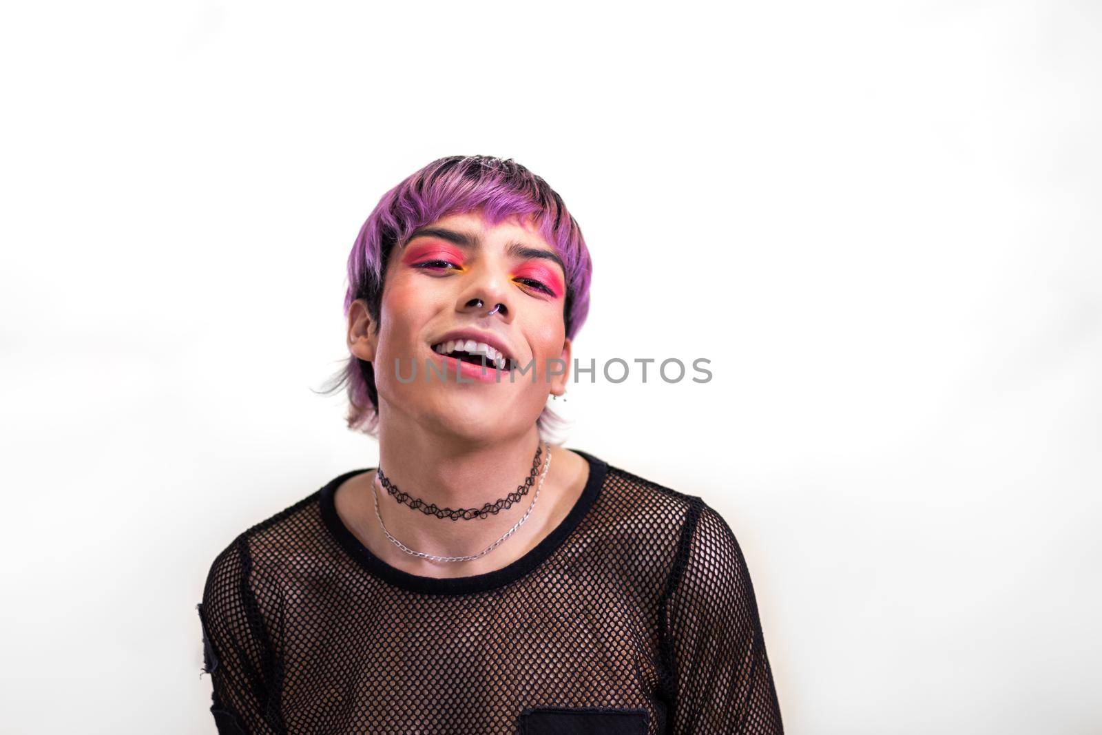 Young man with hot pink eye make up and purple hair with cool attitude looking at camera. Copy space. Non binary and LGBT concept.