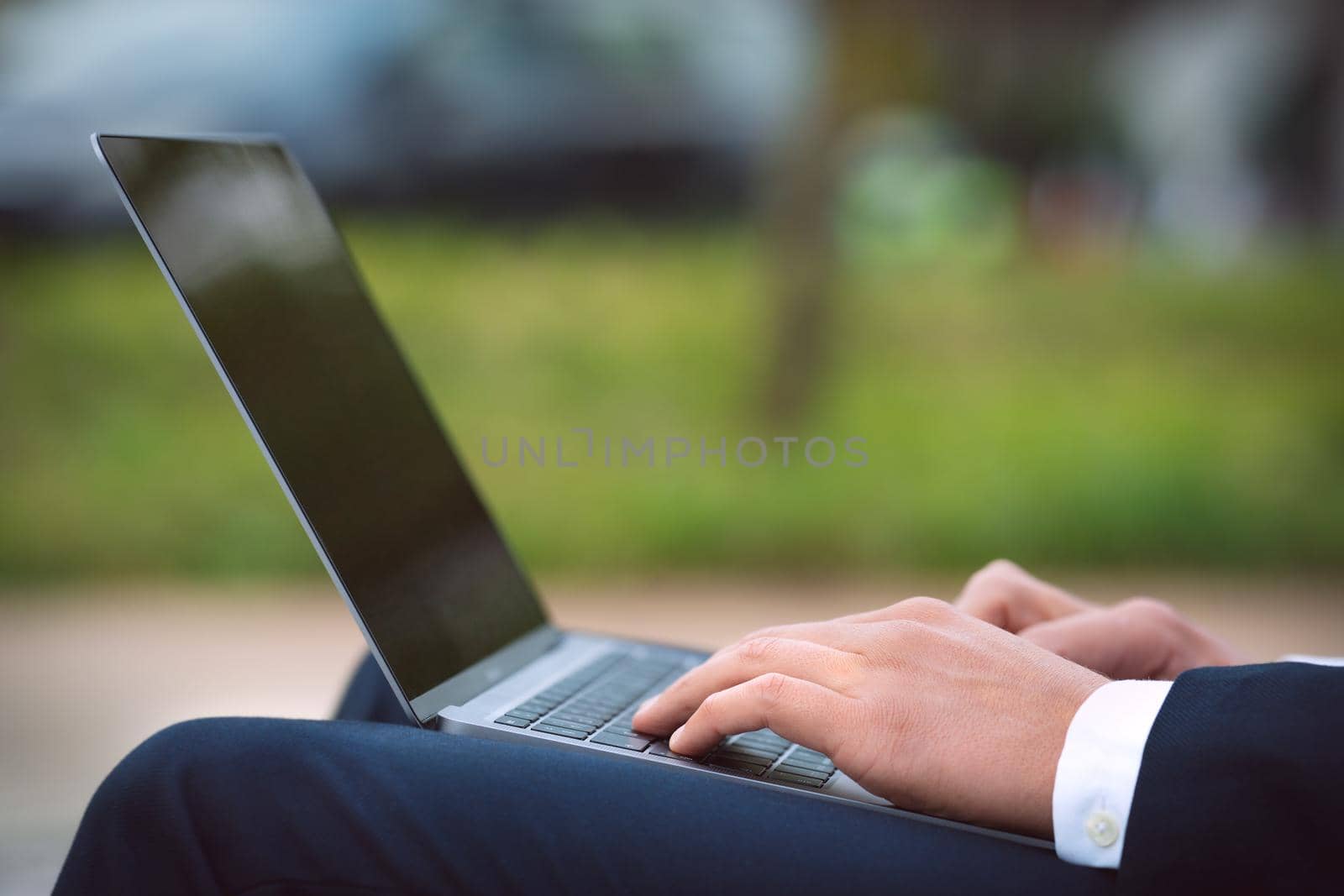 Man working on his laptop outdoors. Business man hands typing on computer. High quality photo