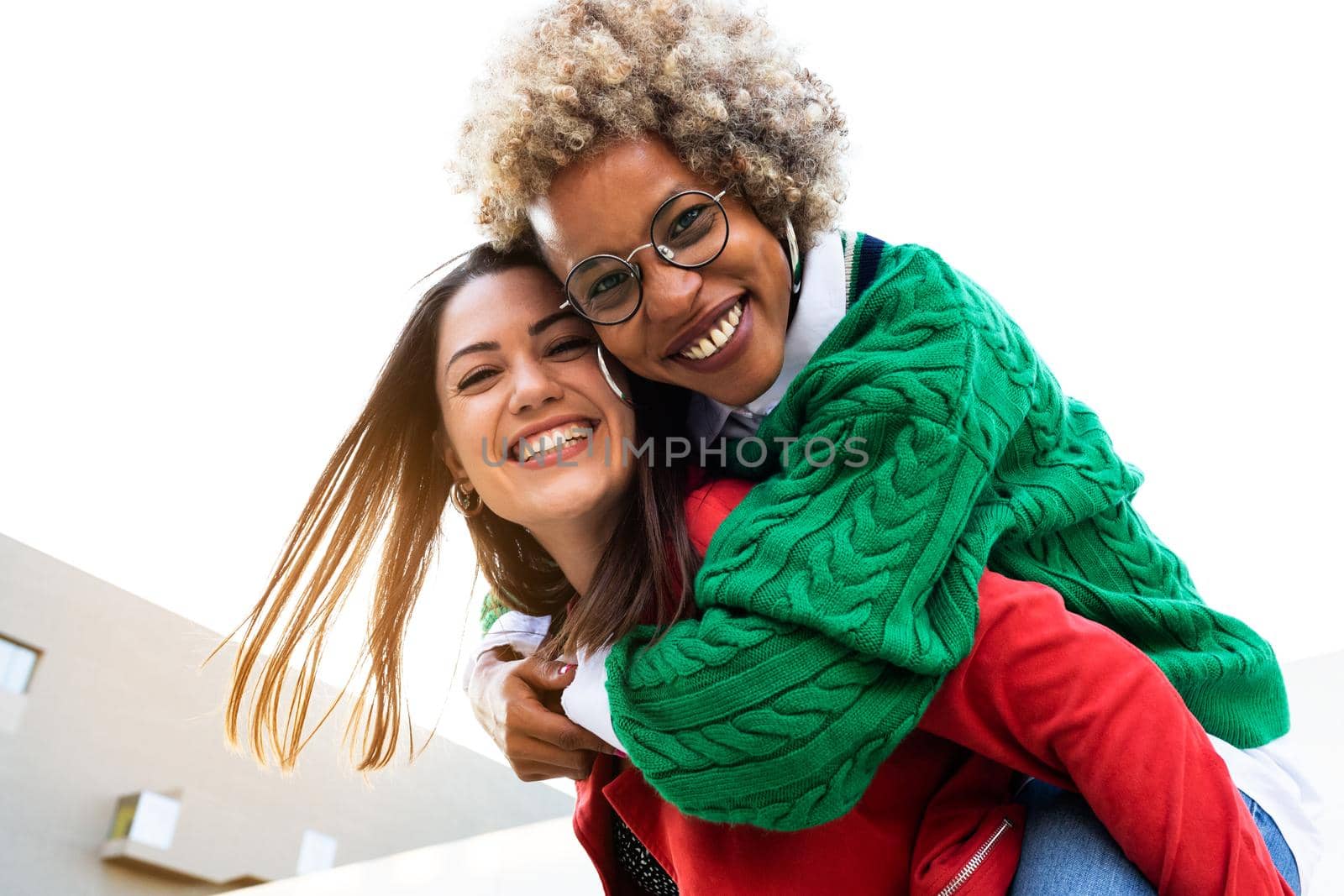 Multiracial female lesbian couple. Piggyback ride with girlfriend. Copy space. by Hoverstock